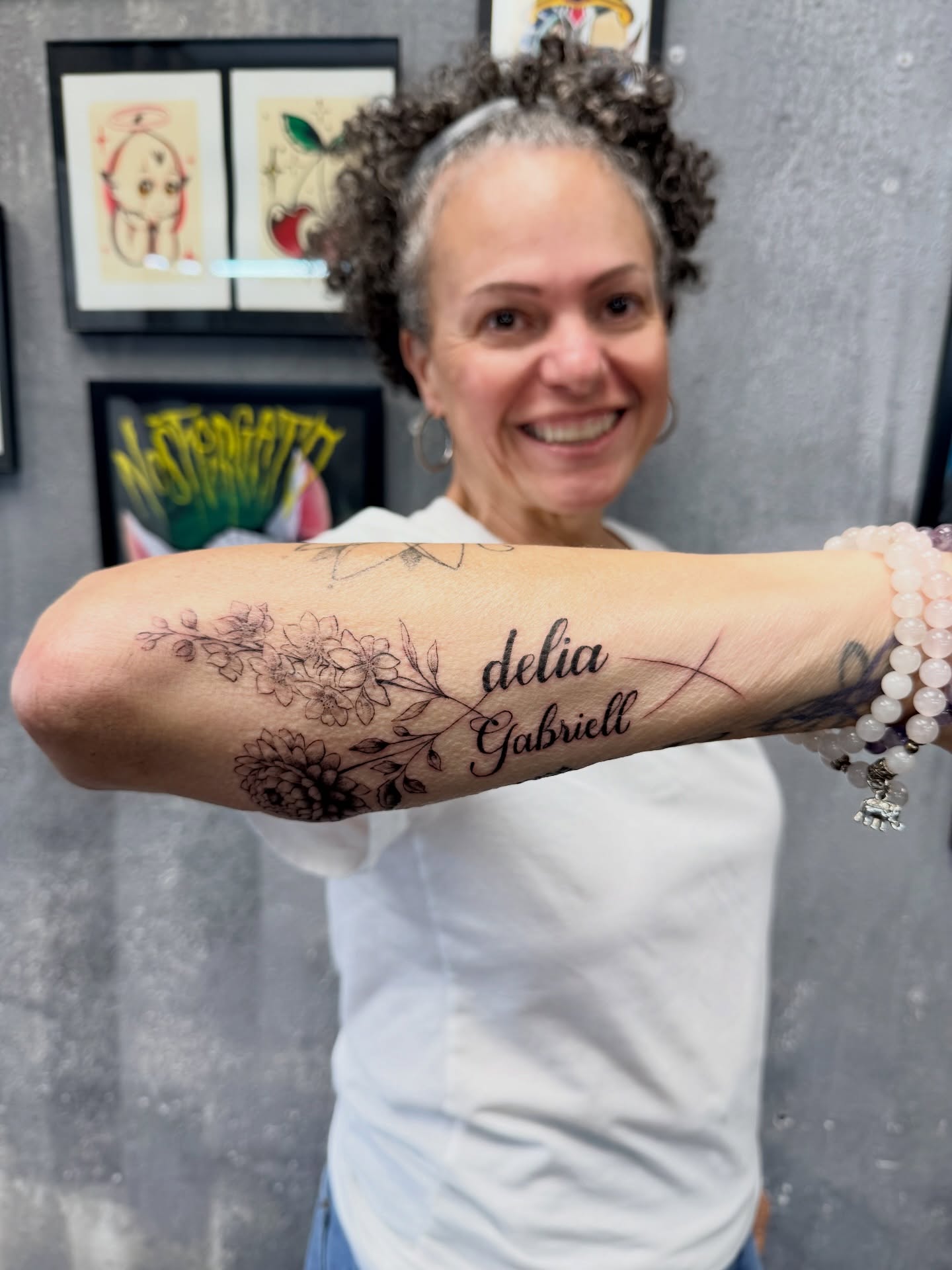 Floral design with names black and grey tattoo on the forearm by Chris