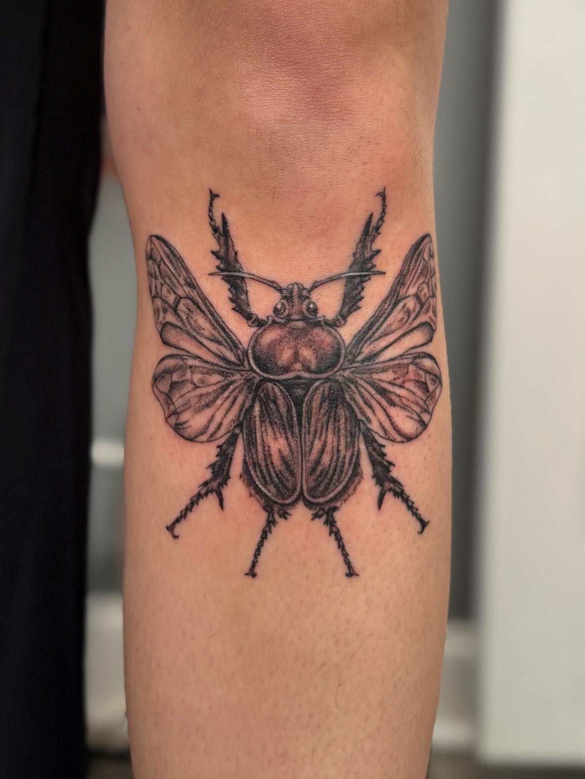 Beetle black and grey tattoo on the forearm by Kamakana Pankiwska