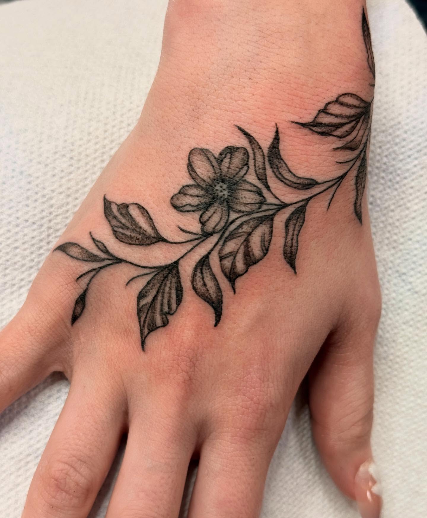 Flower branch black and grey tattoo on the hand by Megan Sue Causemaker