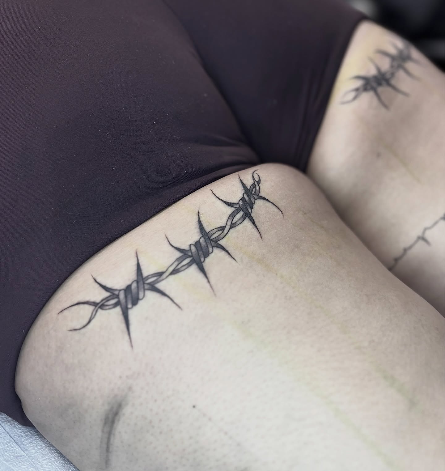 Barbed wire black and grey tattoo on the thigh by Weho Tattoo Artist Lupe