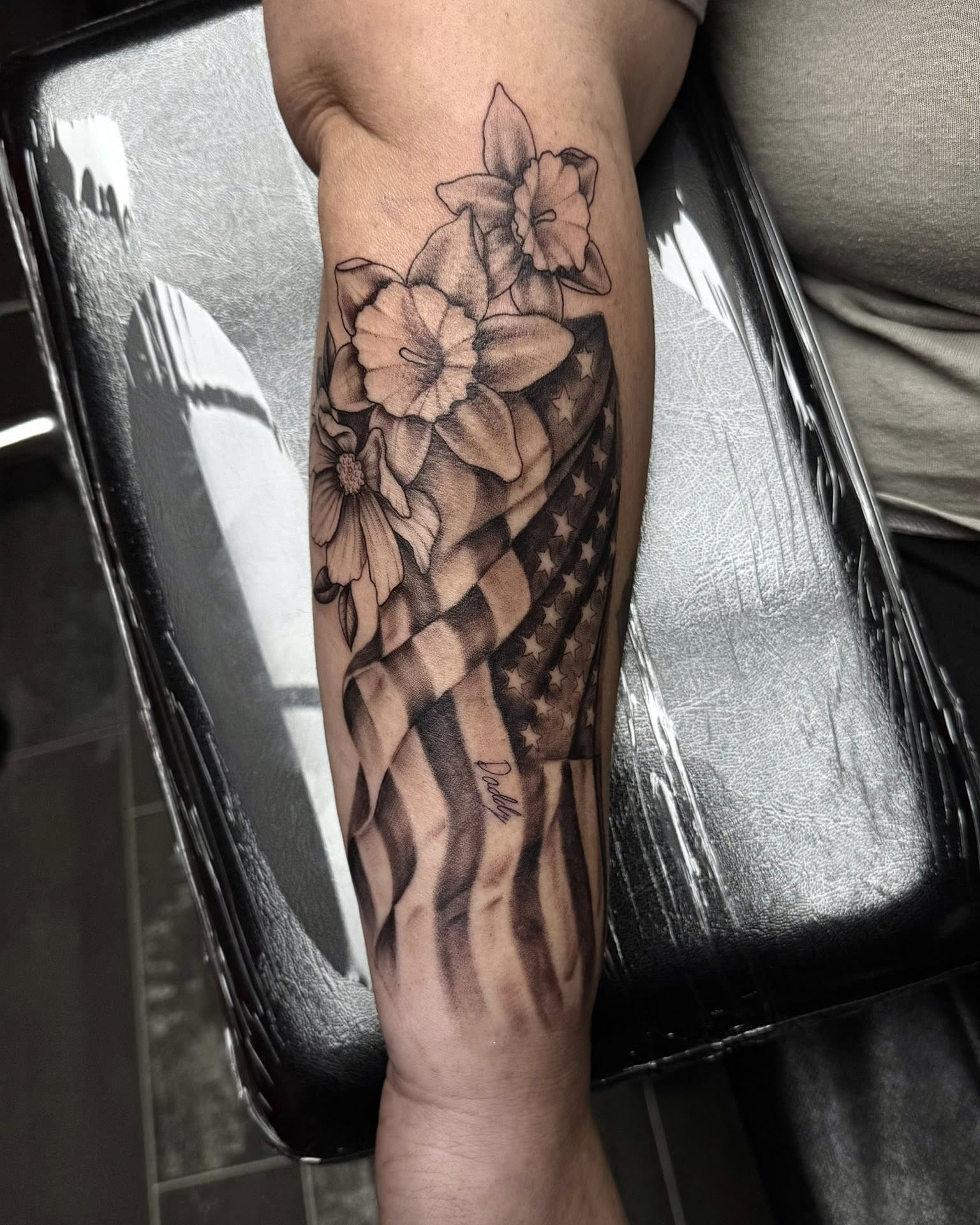 Flowers and American flag realism tattoo on the forearm by Madison Jasso
