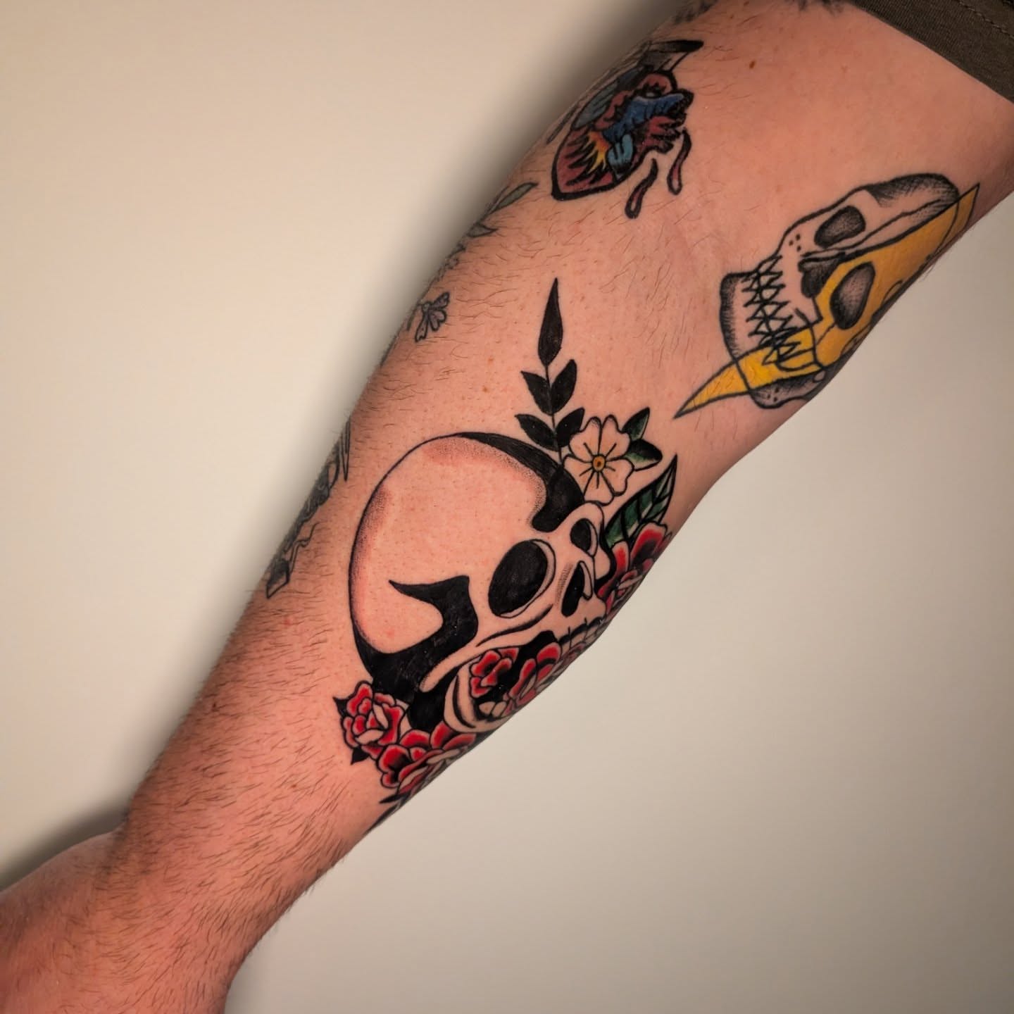 Skull and flowers American traditional tattoo on the forearm by Arminda Walborn