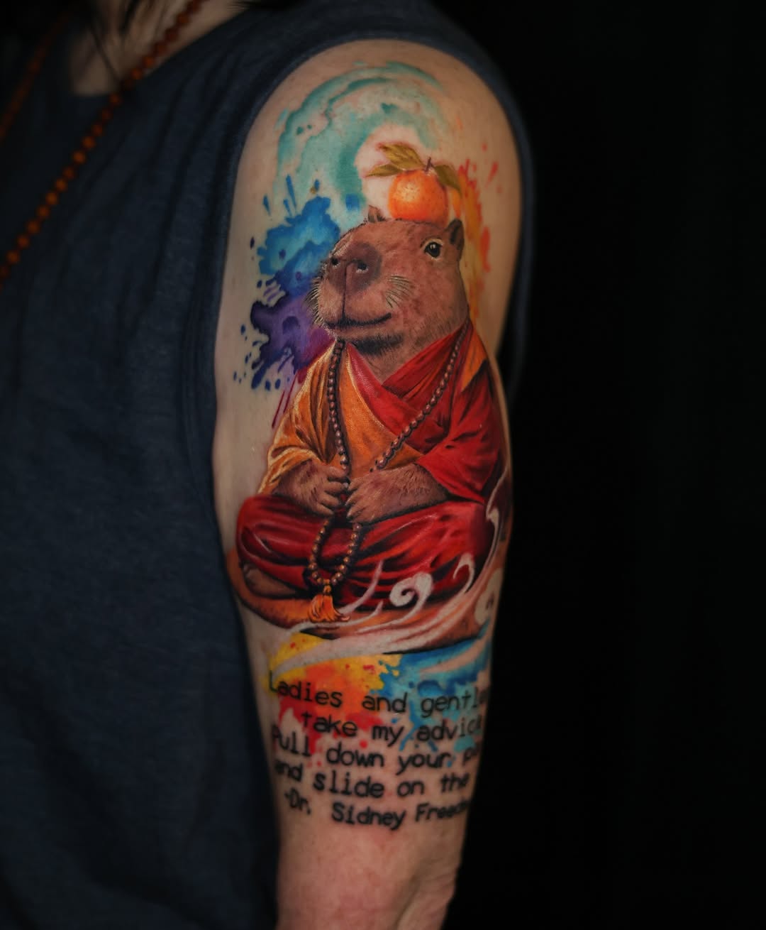 Capybara monk with orange and quote watercolor tattoo on the forearm by Ksu Storm, San Francisco, California