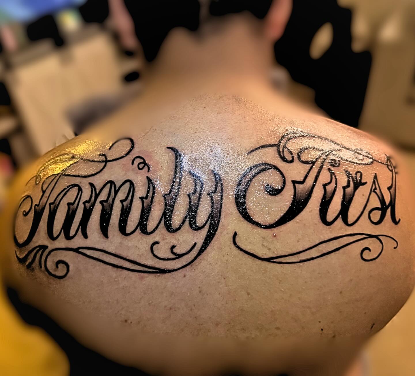 Family First lettering script tattoo on the back by MY$T