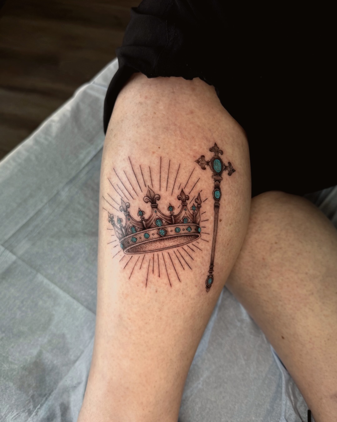 Crown and scepter black and grey tattoo on the thigh by Ingrid Rojas