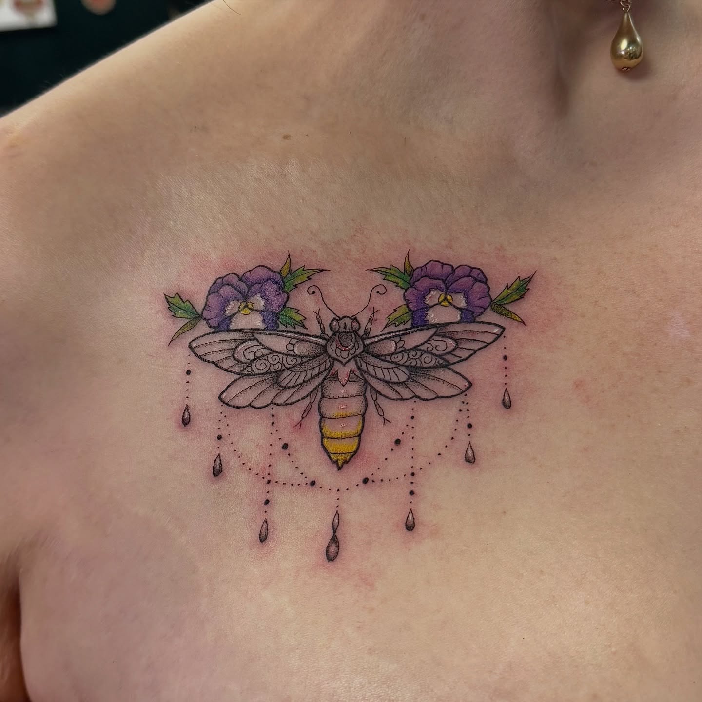 Moth and pansies dotwork tattoo on the chest by Kat Bennett