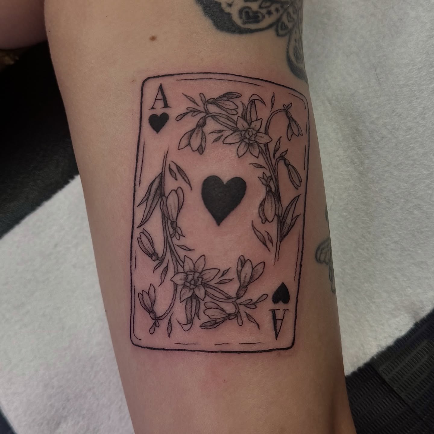 Ace of hearts black and grey tattoo on the forearm by Kat Bennett