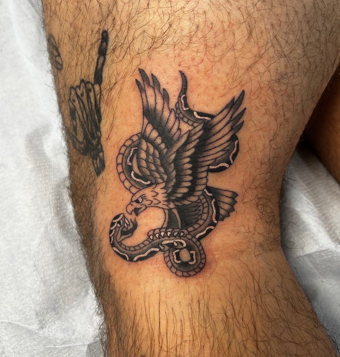Eagle and snake black and grey tattoo on the thigh by Tawni Bender