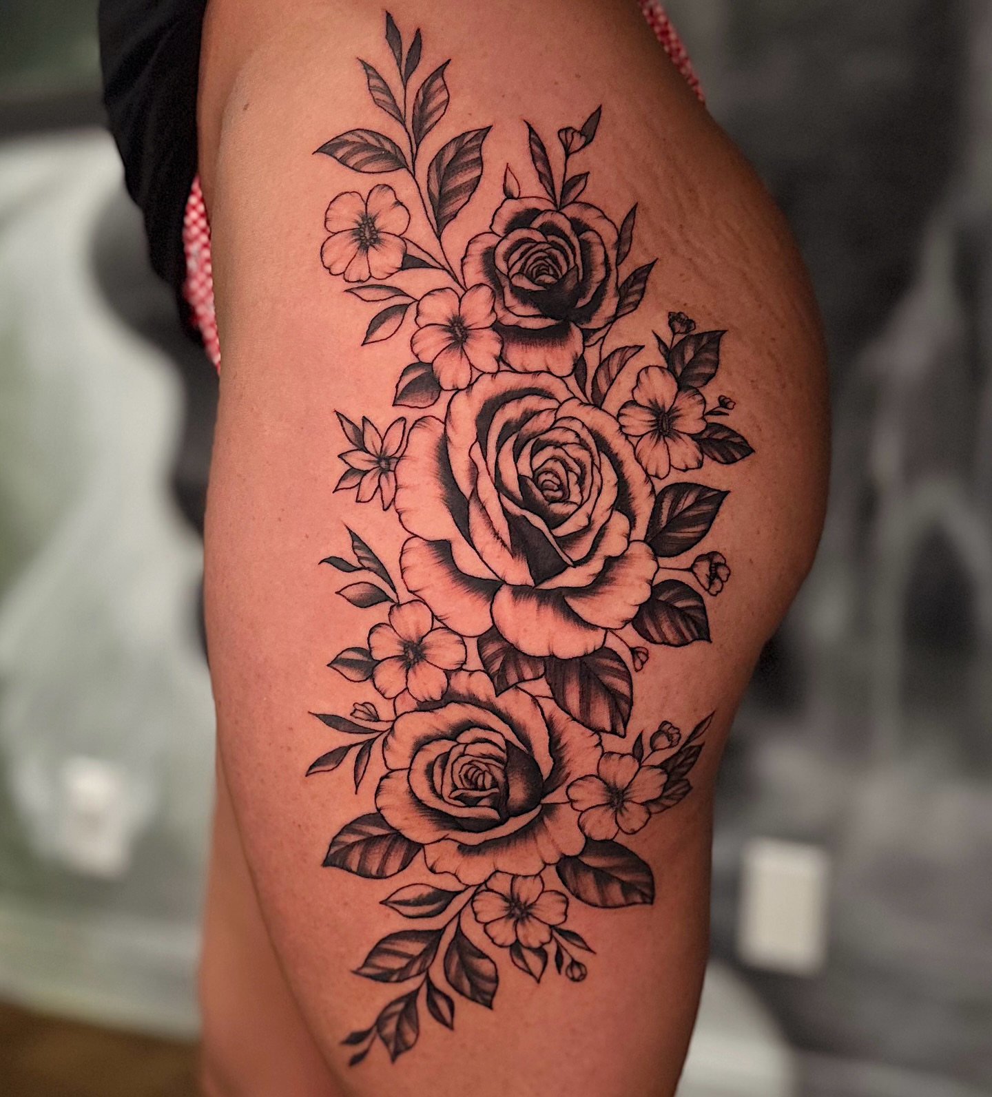 Roses and flowers black and grey tattoo on the thigh by Breanna Werner
