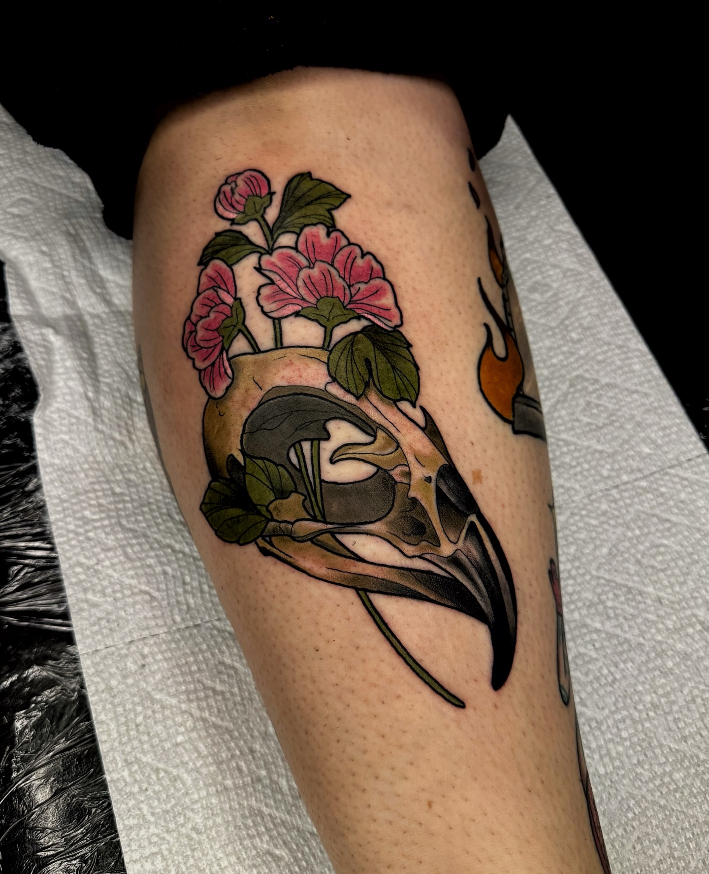 Bird skull and flowers American traditional tattoo on the forearm by Brett Brown