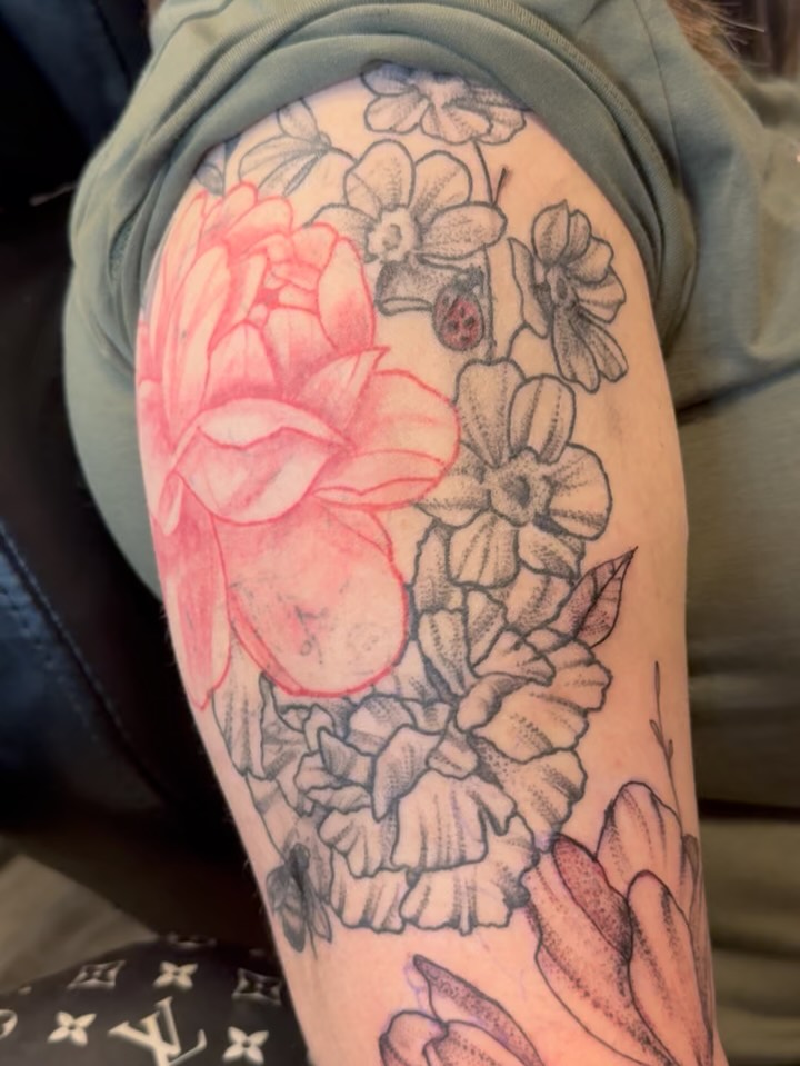 Floral arrangement black and grey tattoo on the upper arm by Lexy