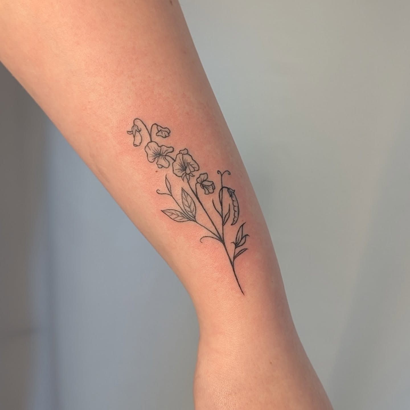 Flowers fine line tattoo on the forearm by Nenookaasi Martin