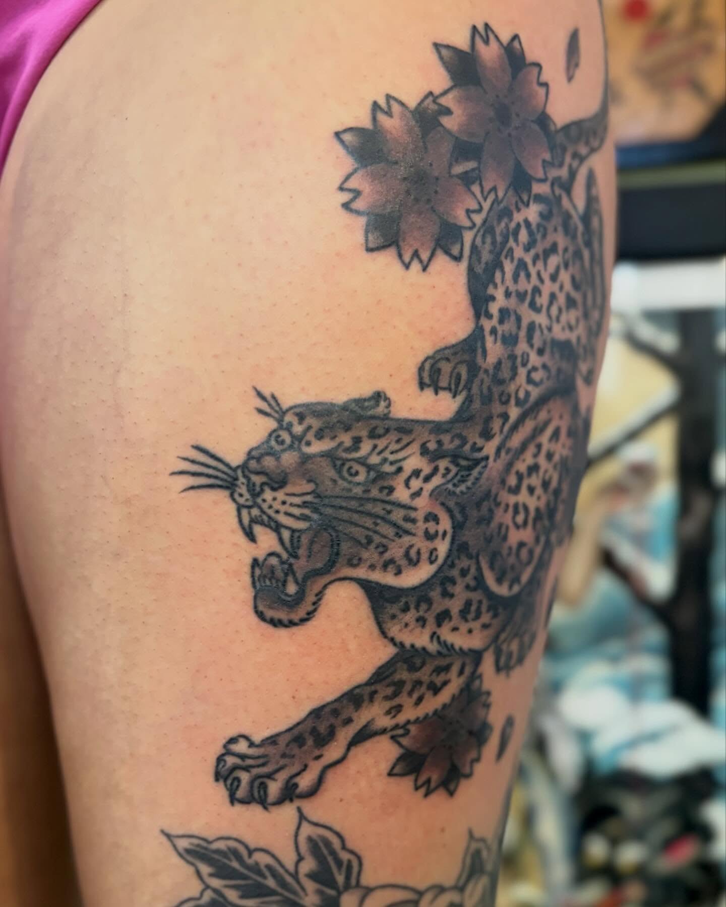 Leopard and flowers black and grey tattoo on the upper arm by Tia Cave