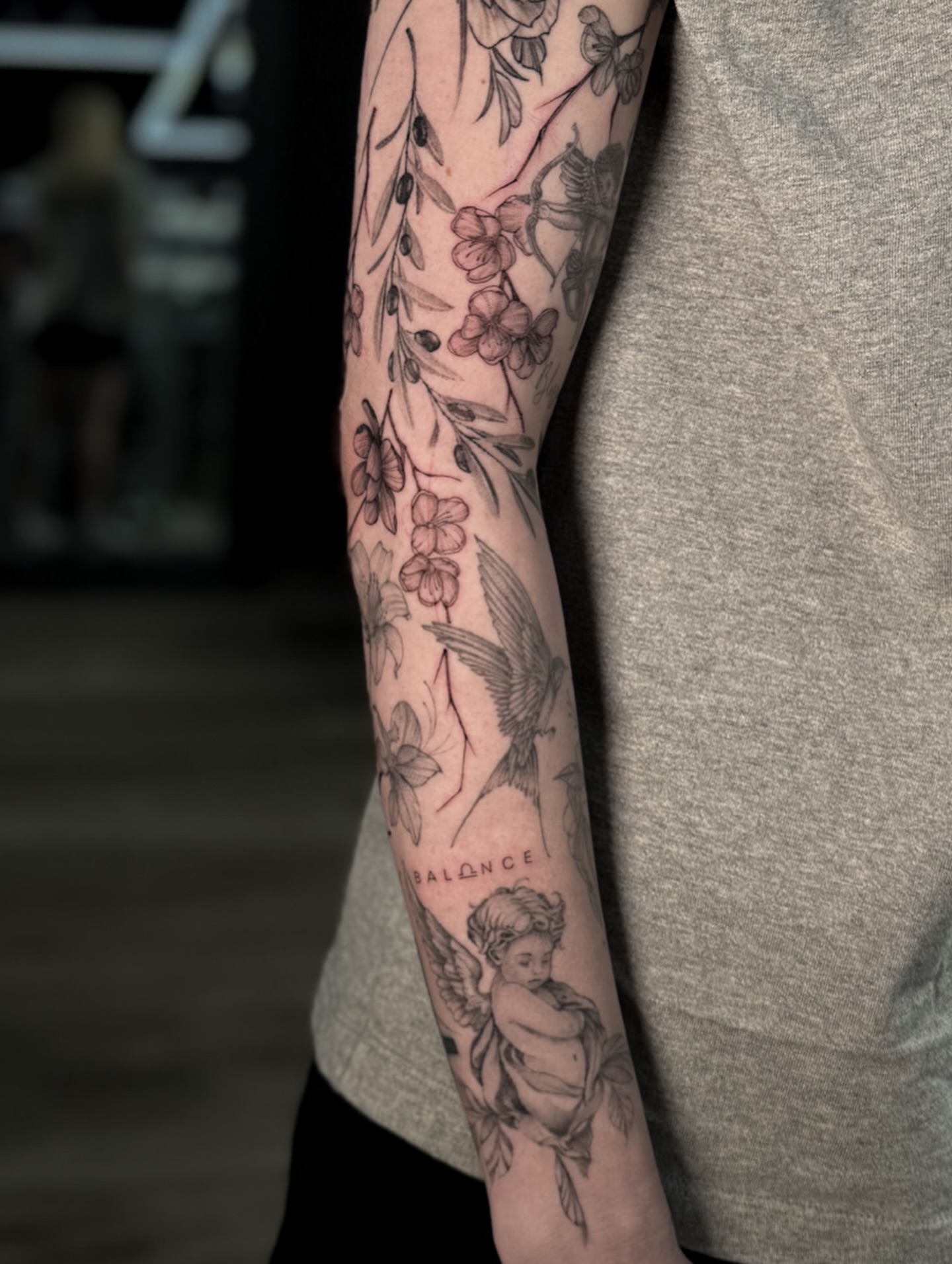 Floral and bird black and grey tattoo on the forearm by Nicolas Herrera
