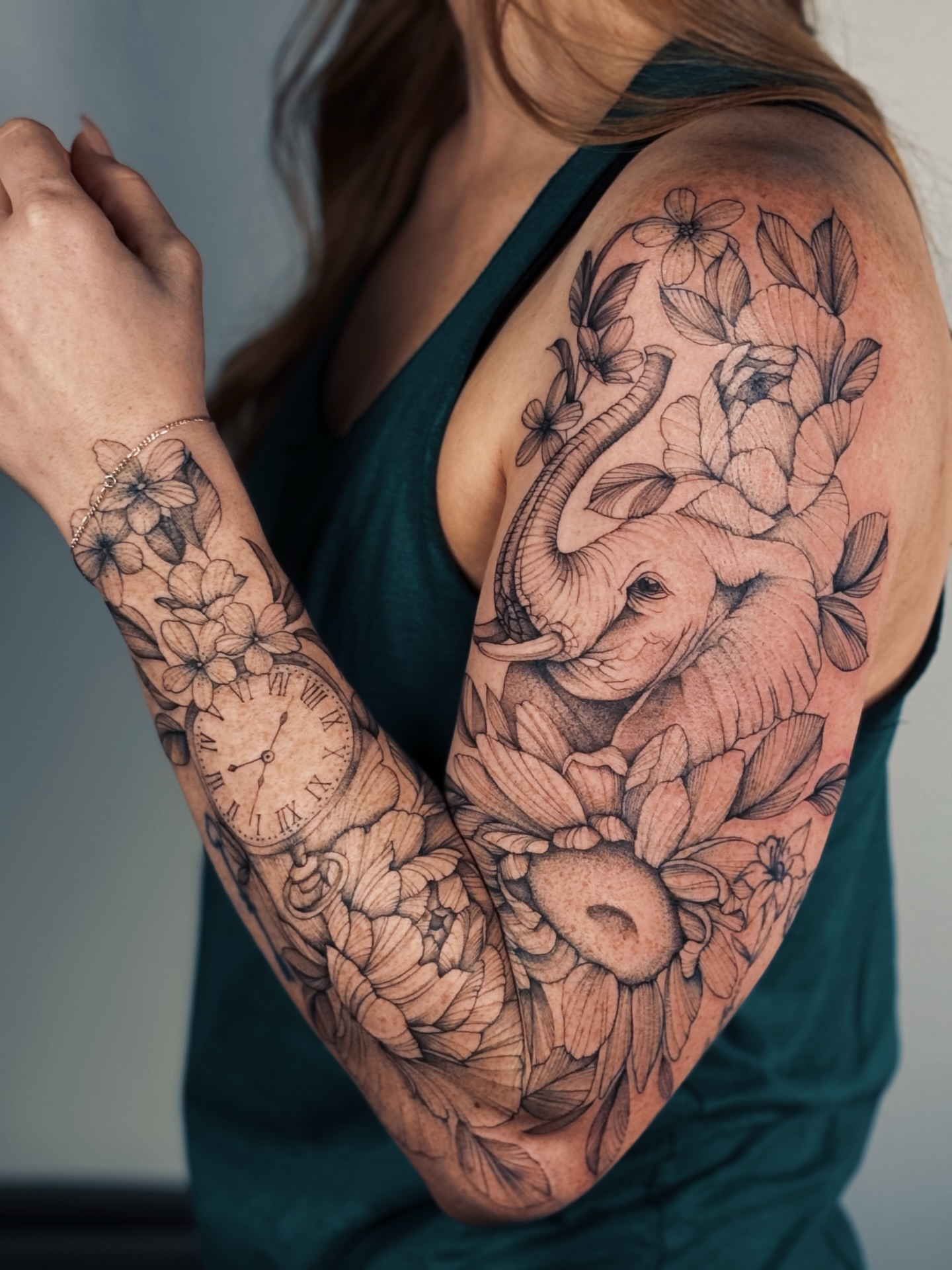 Elephant and floral realism tattoo on the upper arm by Olha Tytarenko