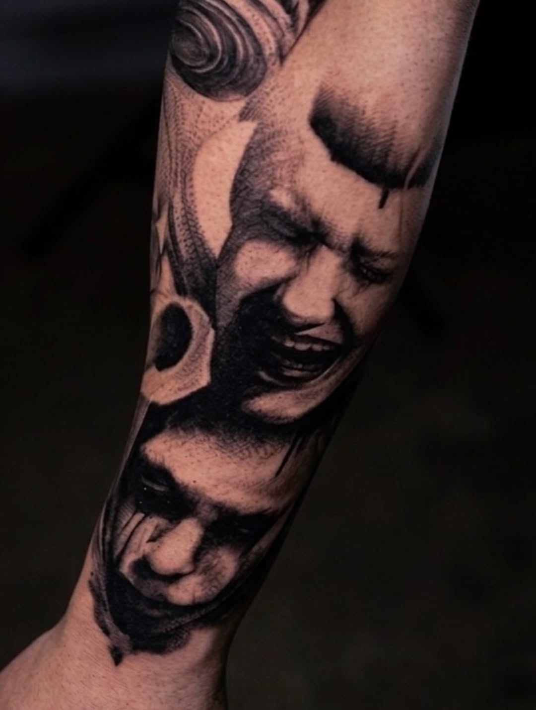 Two faces, one screaming, one crying realism tattoo on the forearm by Aren