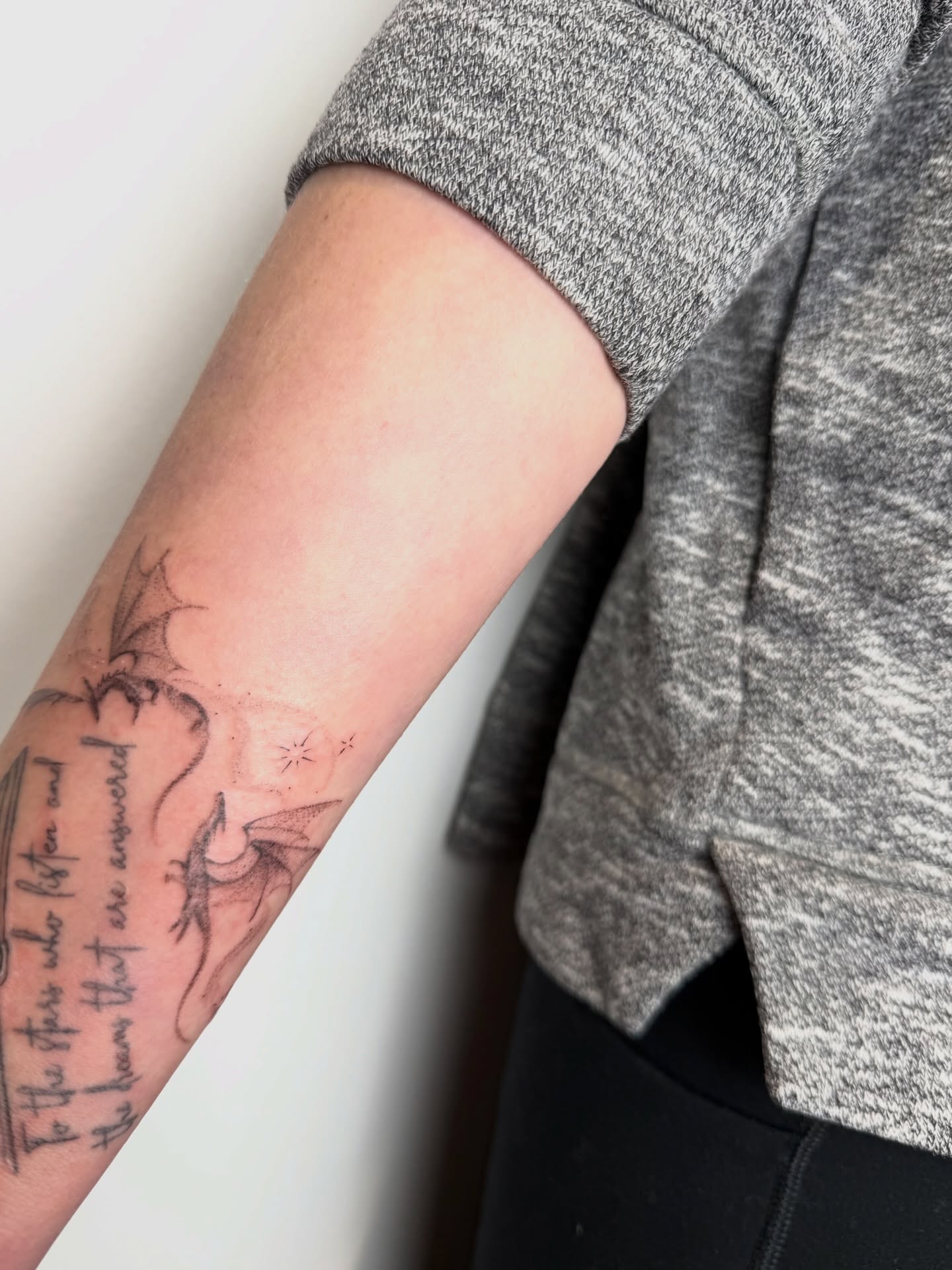 Dragon and stars black and grey tattoo on the forearm by Mackenzie