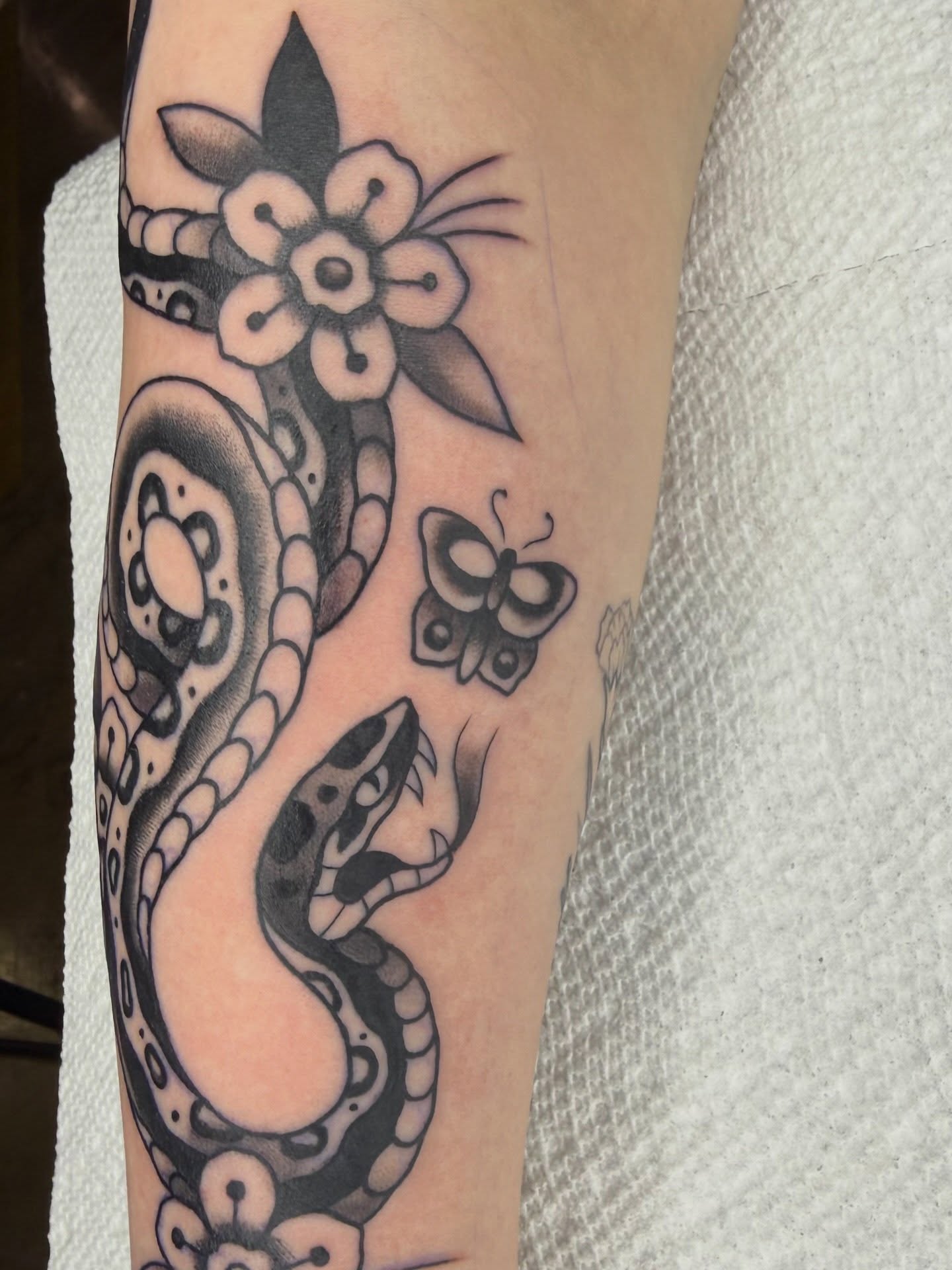 Snake and flower black and grey tattoo on the forearm by @chrisskon, Carpentersville, Illinois