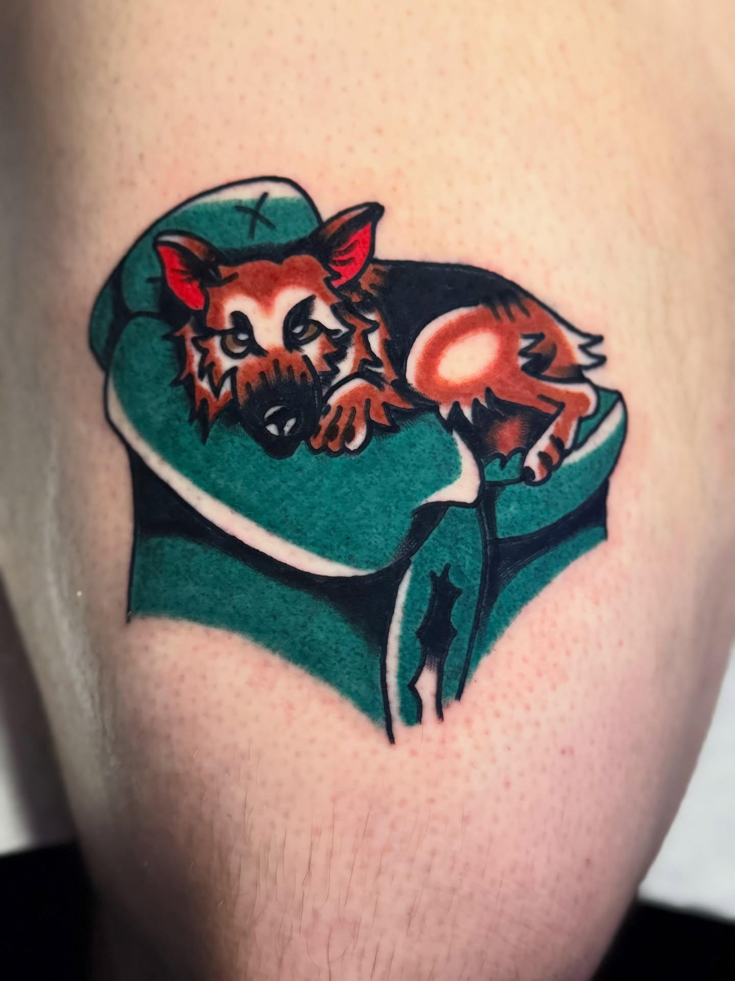 Dog in hat American traditional tattoo on the upper arm by Javin Klingelhoefer Mosley
