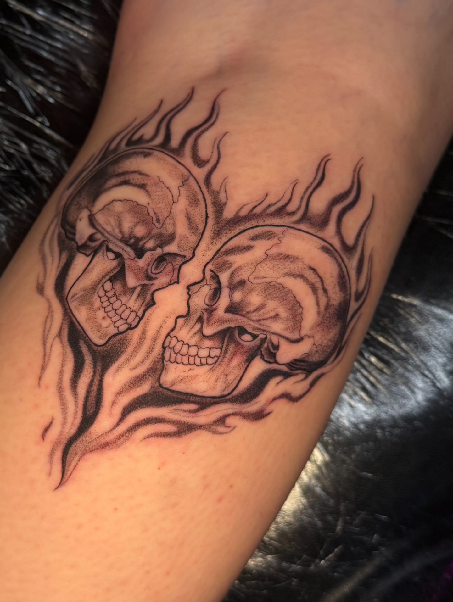 Flaming skulls black and grey tattoo on the forearm by Tattoo Artist Vanessa