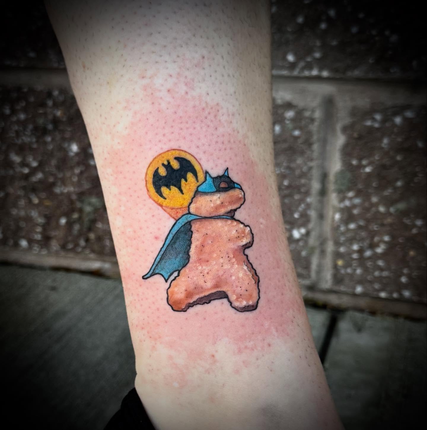 Batman-themed toast watercolor tattoo on the forearm by Jennalea