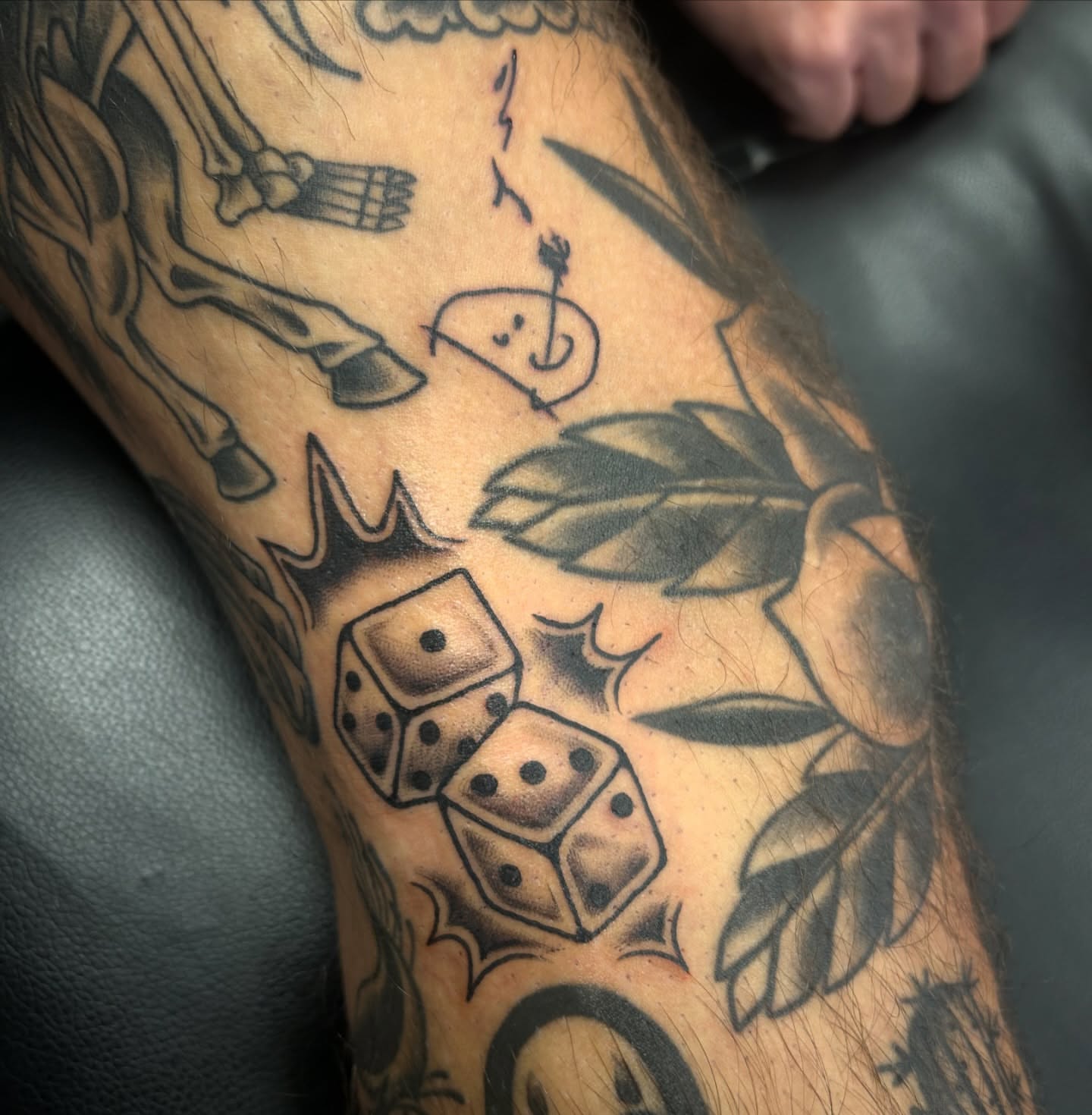 Dice and leaves black and grey tattoo on the forearm by Audrey Migitsch