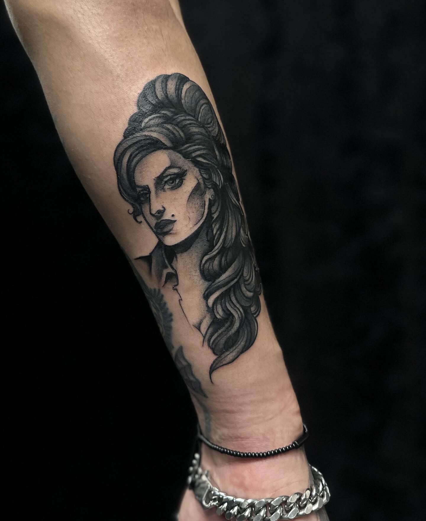 Woman with long hair black and grey tattoo on the forearm by Elvira Savchuk