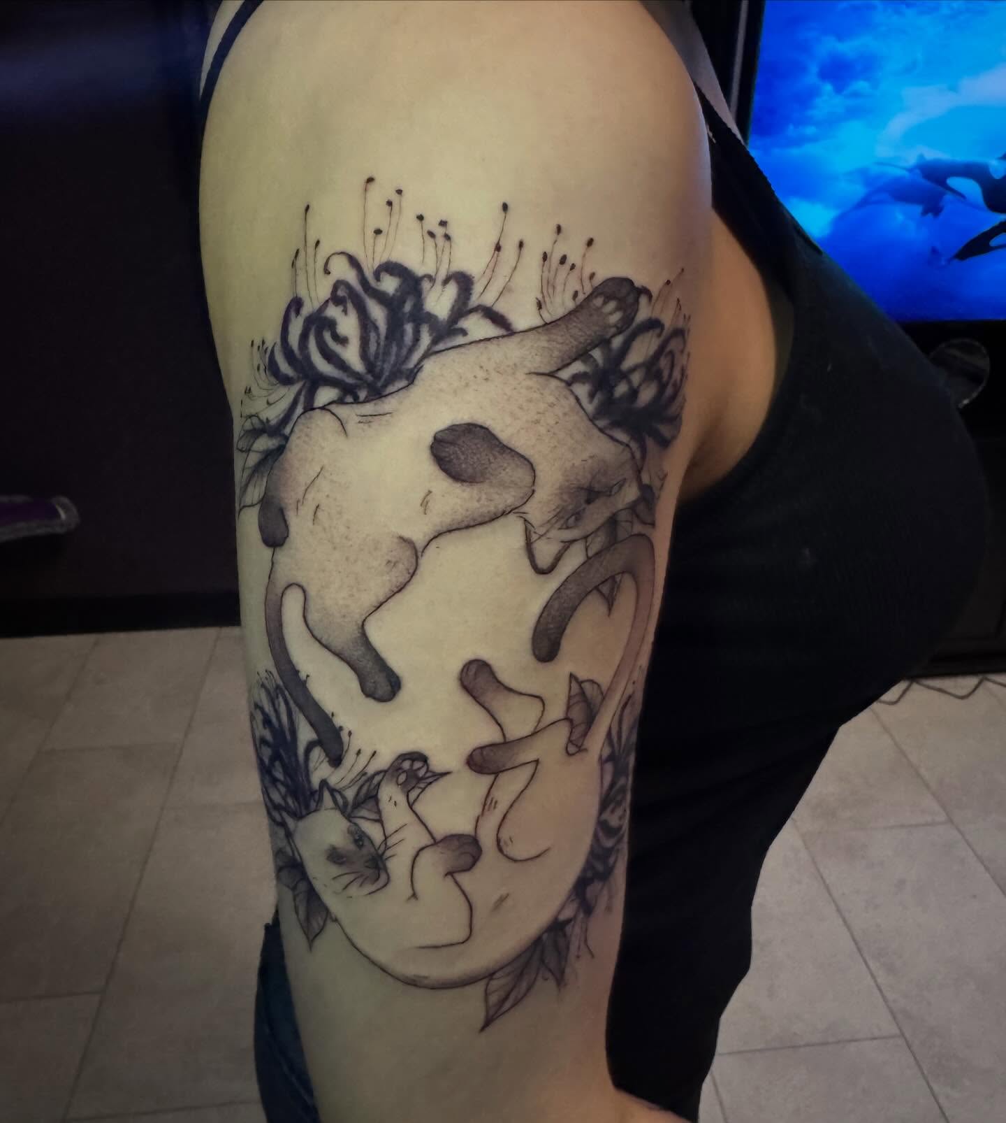 Cat and flowers black and grey tattoo on the upper arm by Lindsay