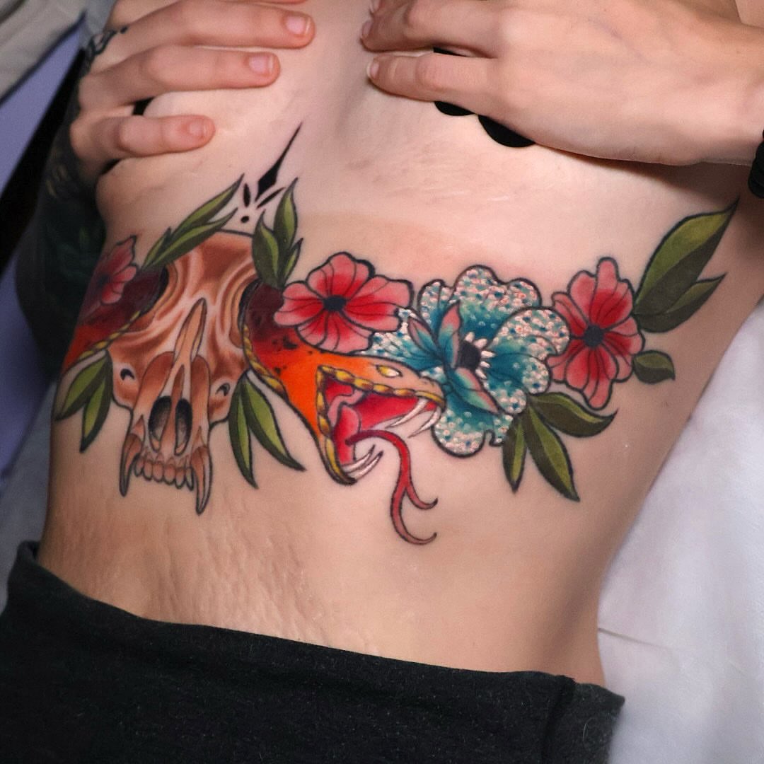 Skull and flowers American traditional tattoo on the ribs by Bailey Drey