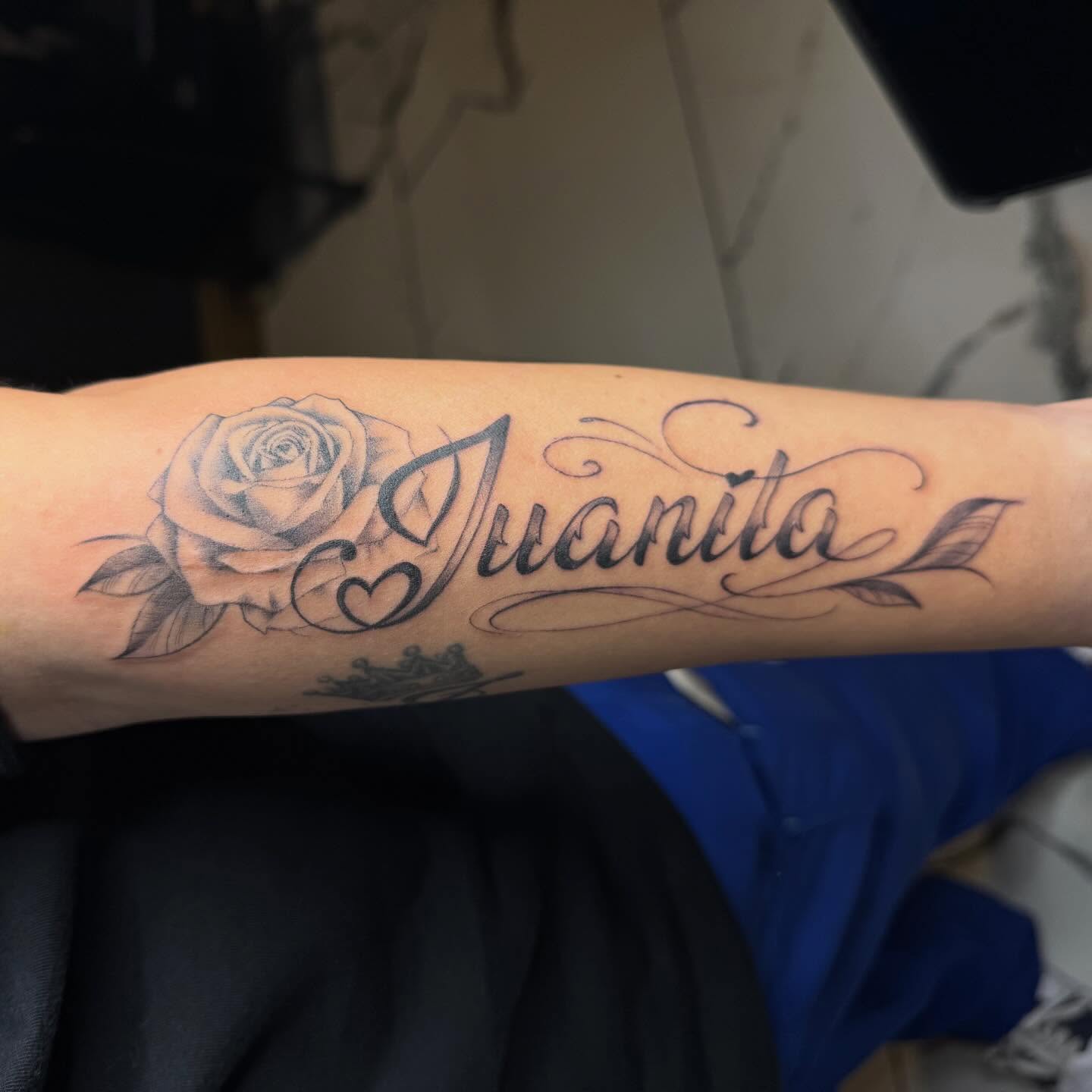 Rose and name black and grey tattoo on the forearm by Marquis Neal