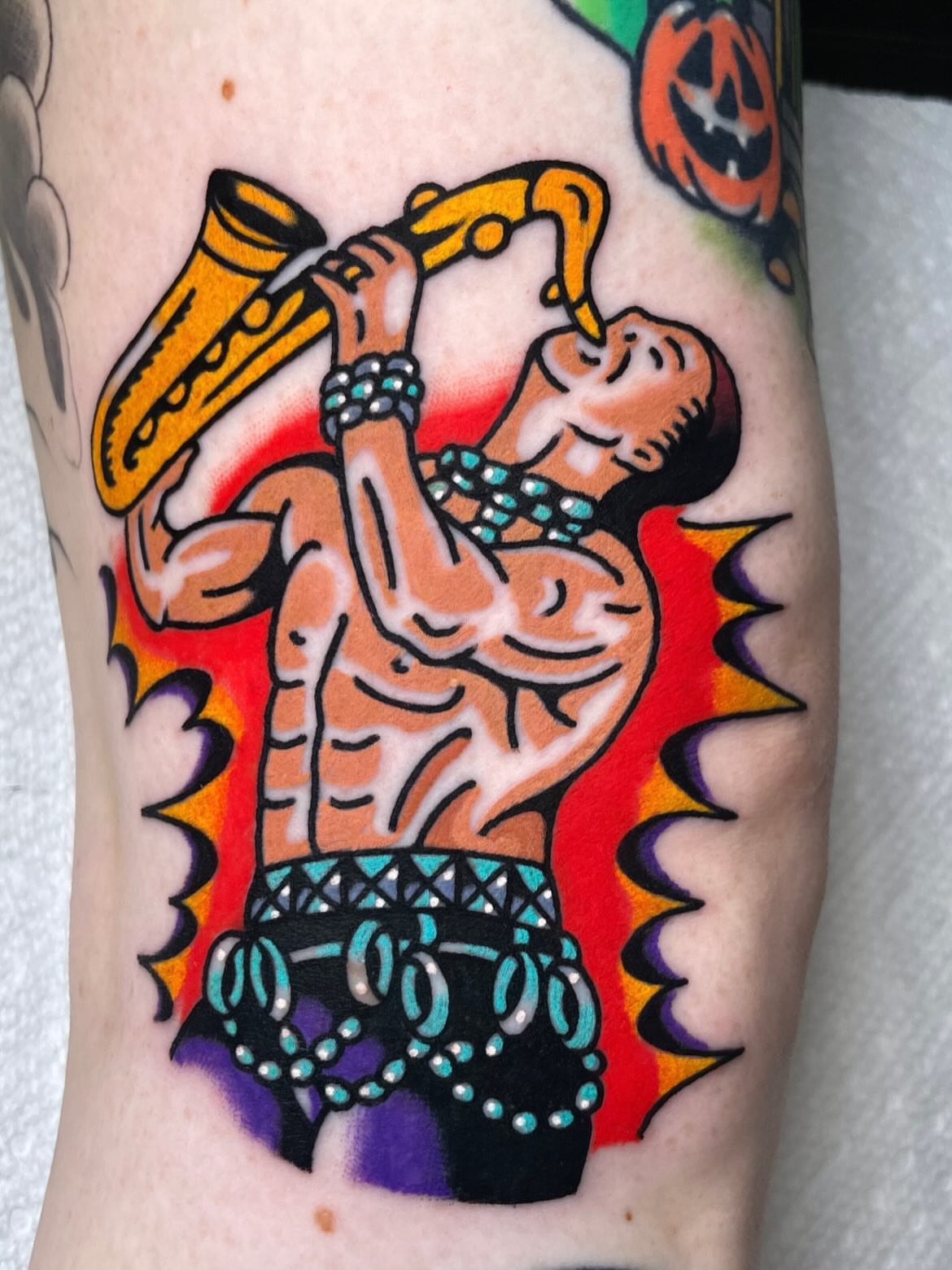 Muscular man playing saxophone American traditional tattoo on the forearm by Ryan McDonald