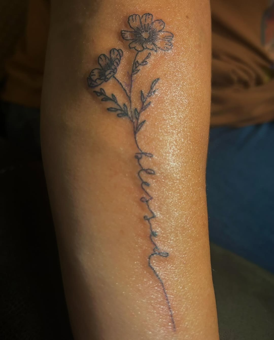 Flowers and script lettering fine line tattoo on the forearm by MY$T