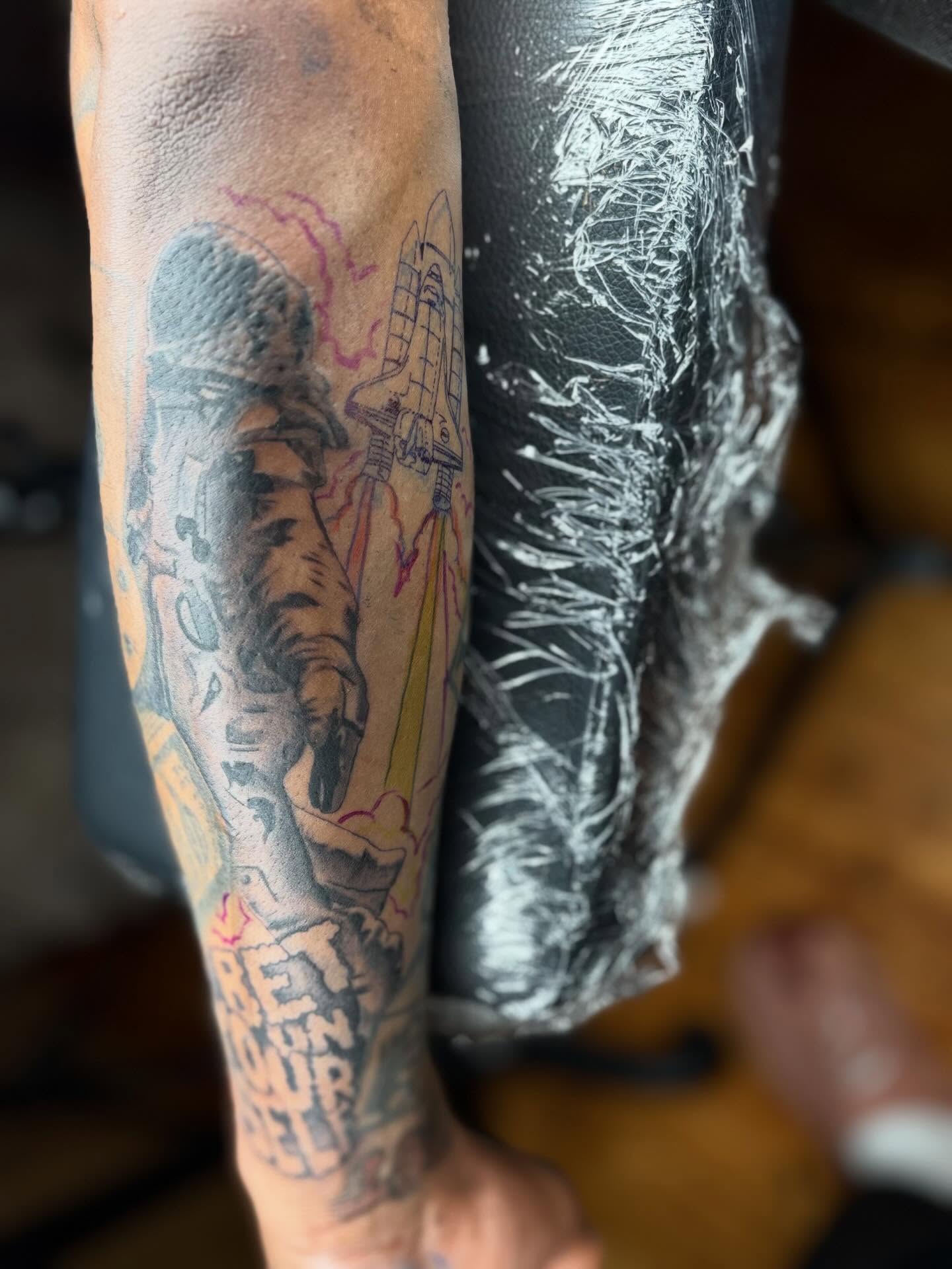 Astronaut and rocket black and grey tattoo on the forearm by Koolz