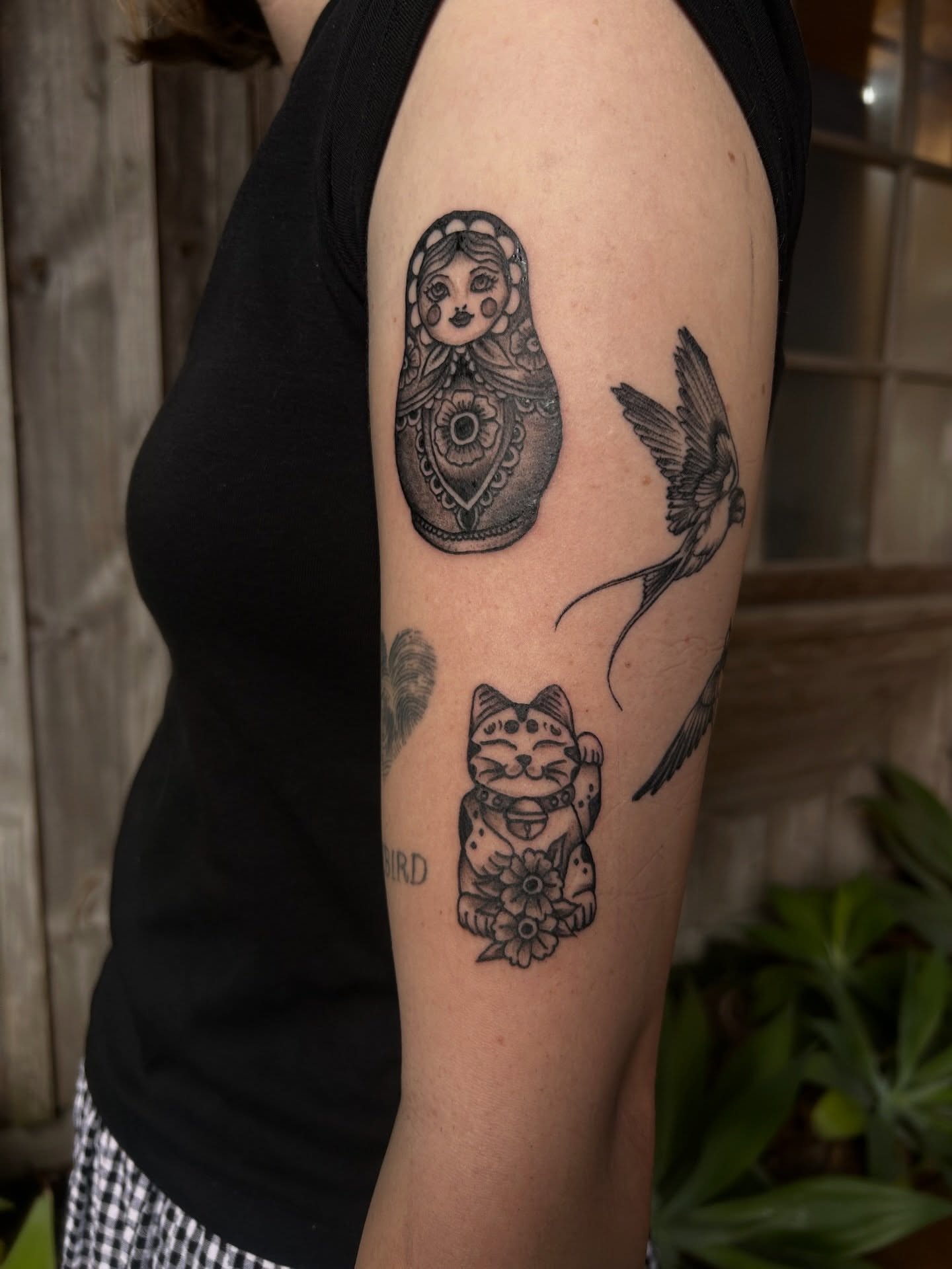 Matryoshka doll, cat, bird black and grey tattoo on the forearm by Amara Lyons, Matakana, New Zealand