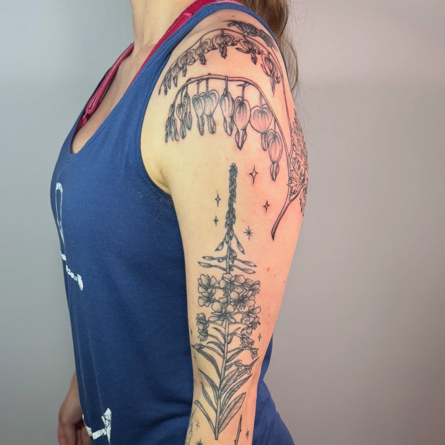 Flower and night sky black and grey tattoo on the upper arm by Jenna Nicole