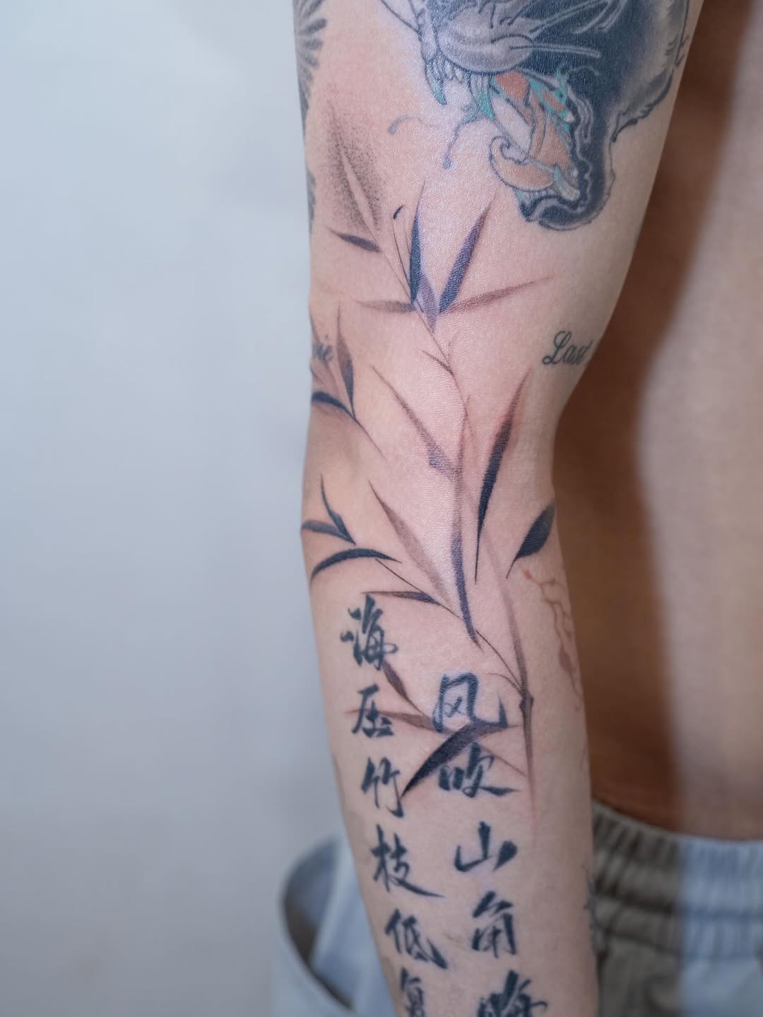 Bamboo and chinese calligraphy blackwork tattoo on the forearm by Tomato