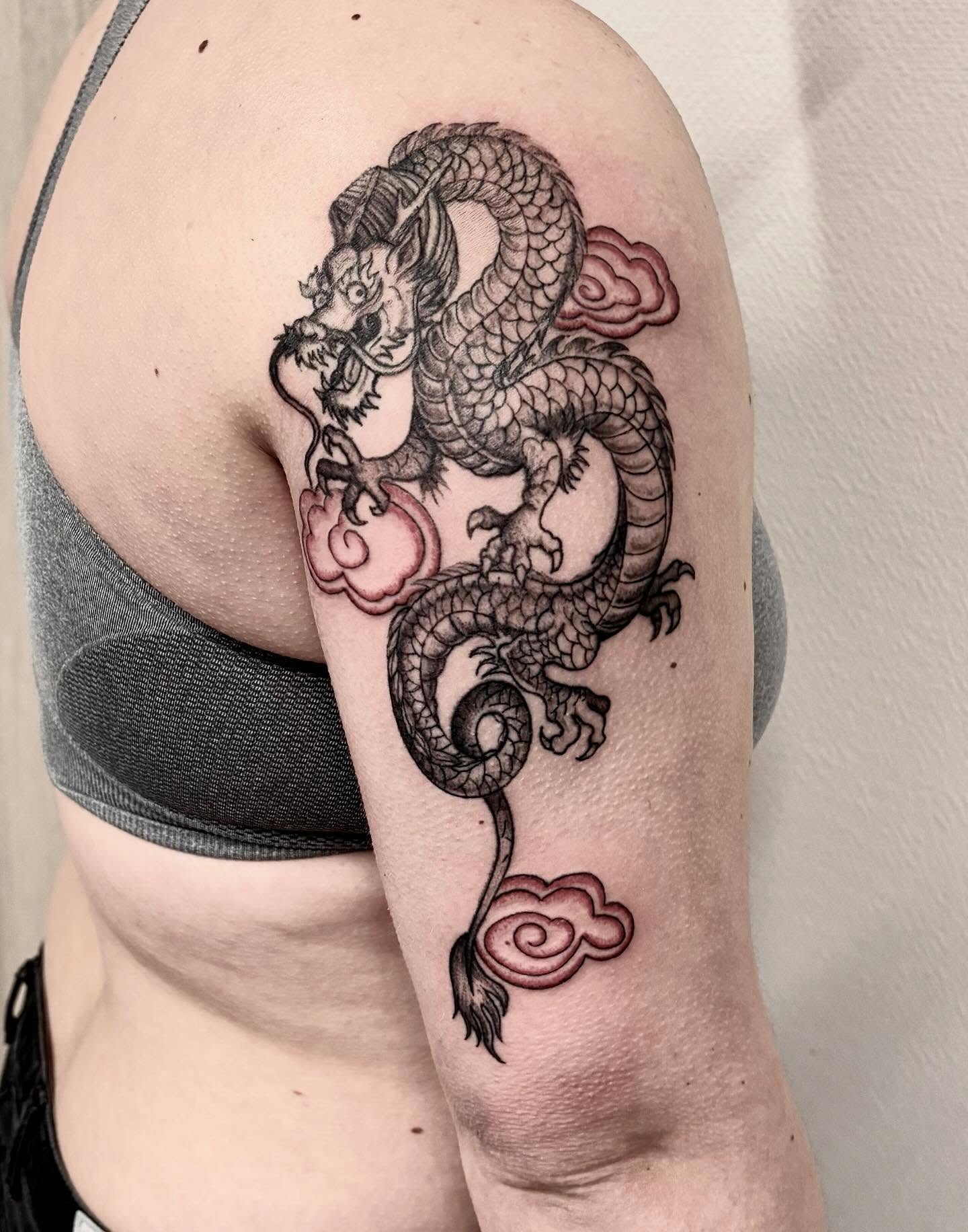 Dragon black and grey tattoo on the upper arm by Deborah