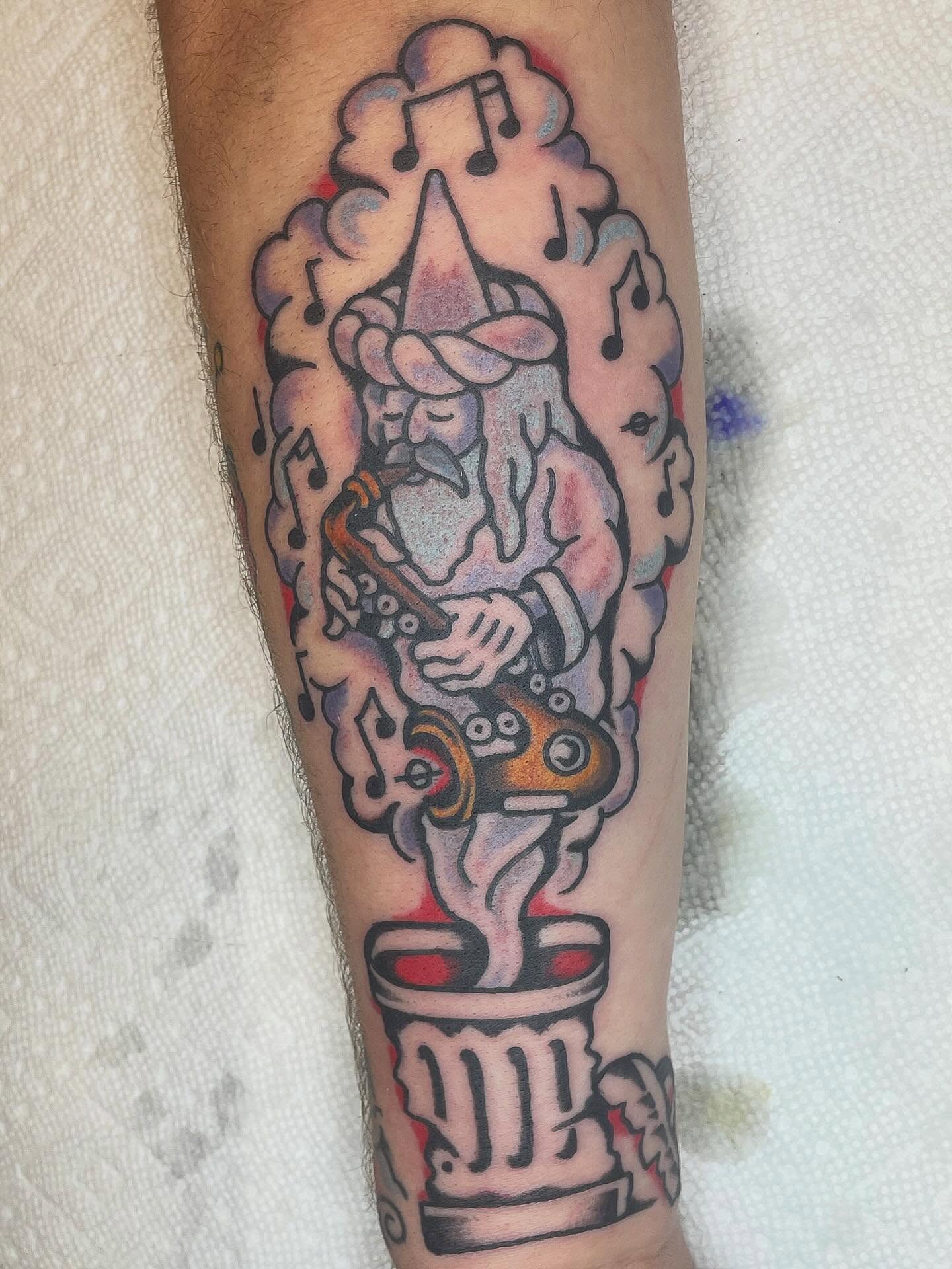 Jester playing saxophone American traditional tattoo on the forearm by Nicholas M. Passeri