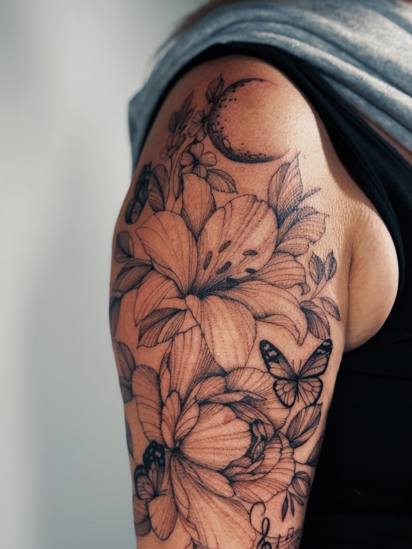 Flowers and butterflies black and grey tattoo on the shoulder by Olha Tytarenko