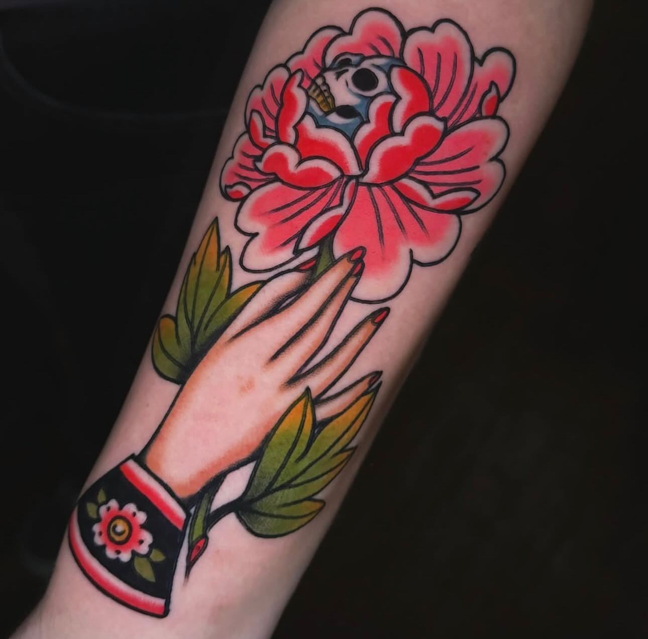 Flower and hand American traditional tattoo on the forearm by Nikki Bee