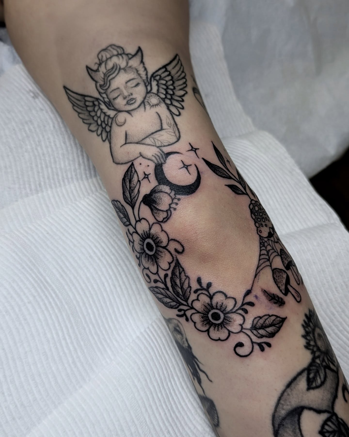 Cherub with moon black and grey tattoo on the forearm by Dani Harkey