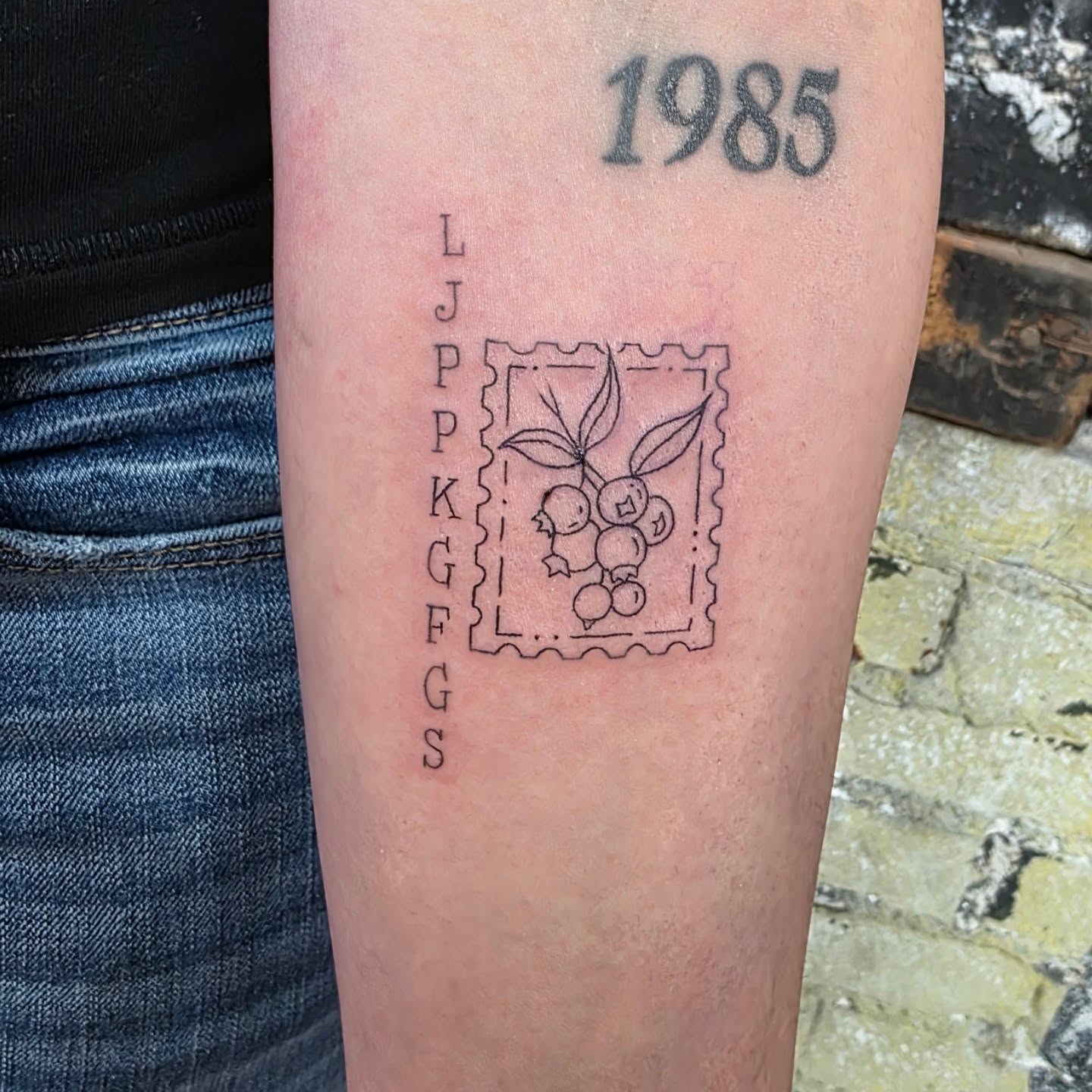 Postage stamp black and grey tattoo on the forearm by Tattoos by Annie