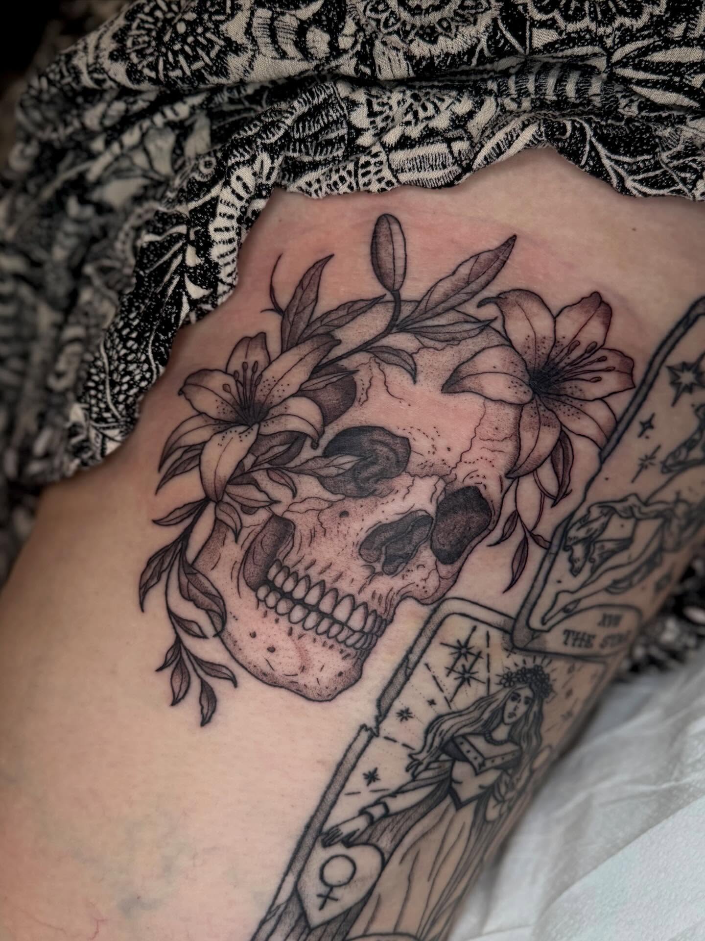 Skull with lilies realism tattoo on the thigh by Brandi 🕷, Mentor, Ohio