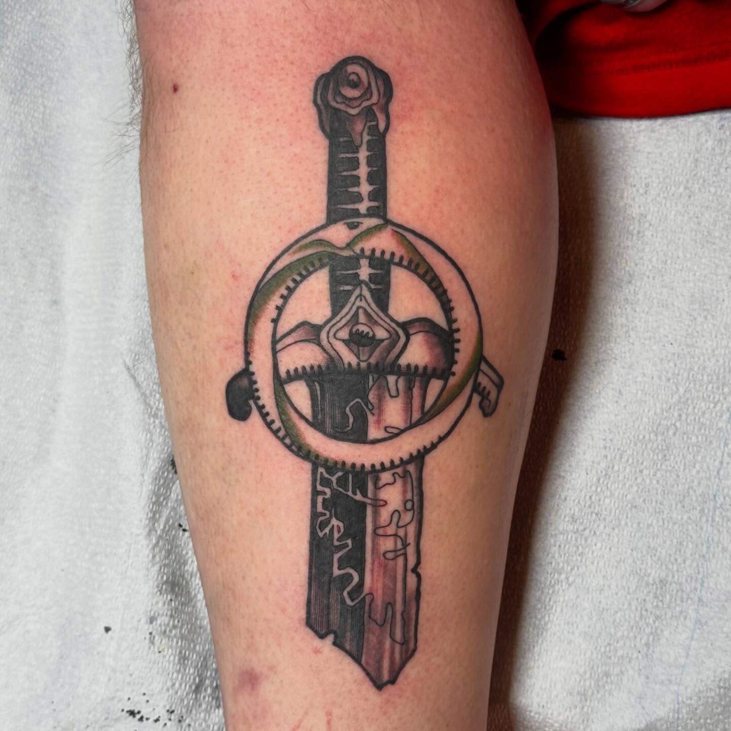 Sword and gear black and grey tattoo on the forearm by Jack Hatchet Tattoos