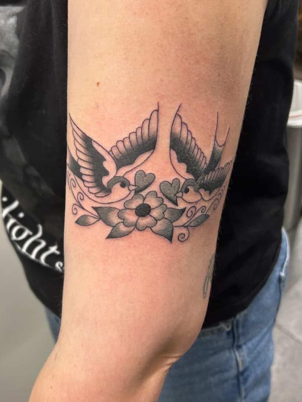 Swallows and flowers black and grey tattoo on the forearm by Tawni Bender