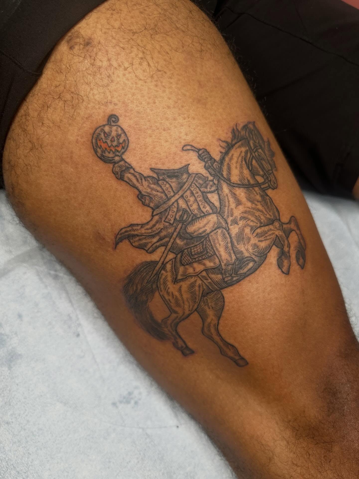 Horseman with pumpkin black and grey tattoo on the thigh by Alex Gunshefski