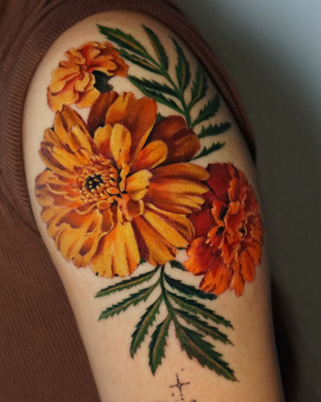 Marigolds realism tattoo on the upper arm by San Diego Color Realism and Neotraditional