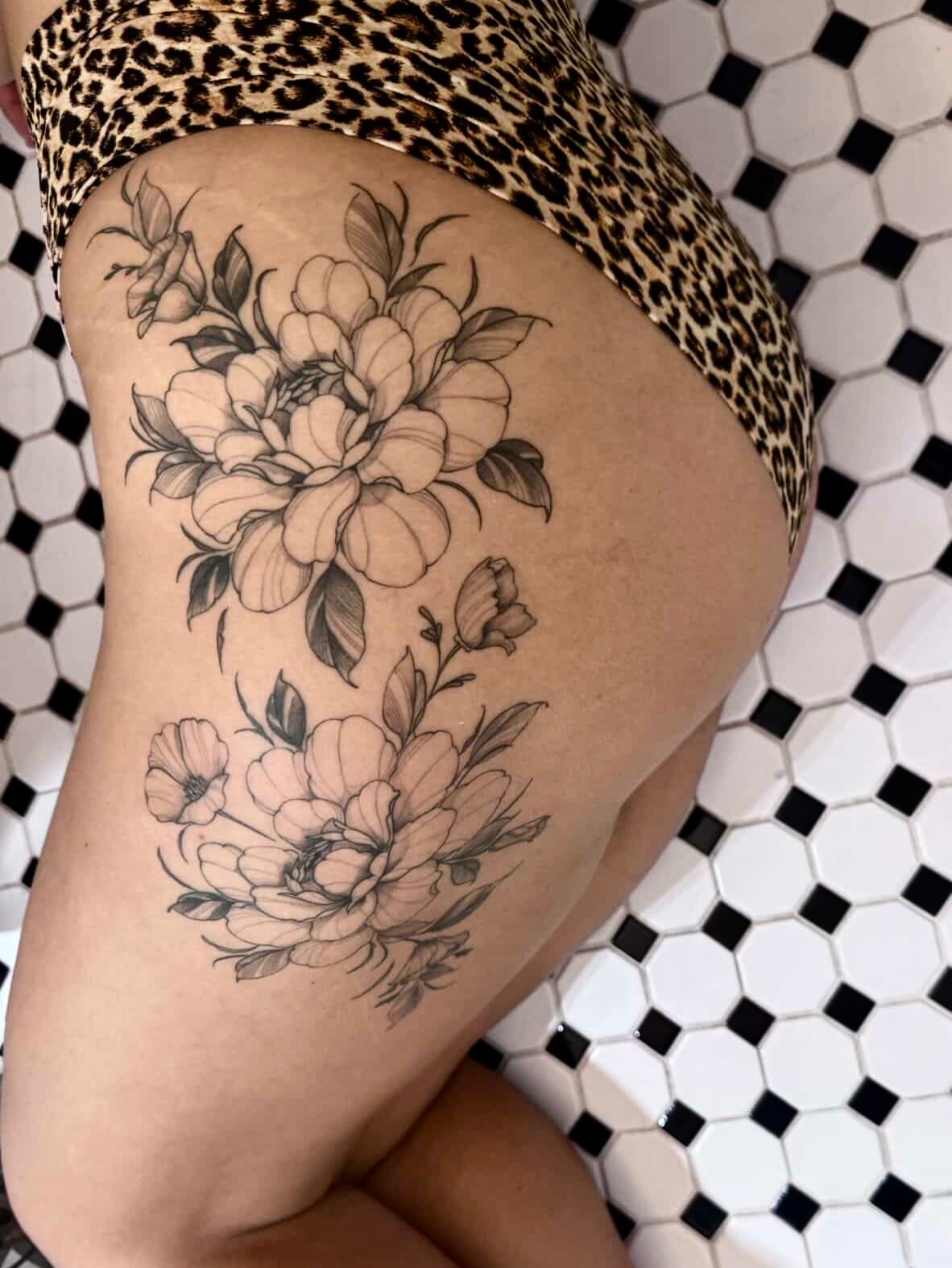 Floral bouquet black and grey tattoo on the thigh by Lo Gwynn