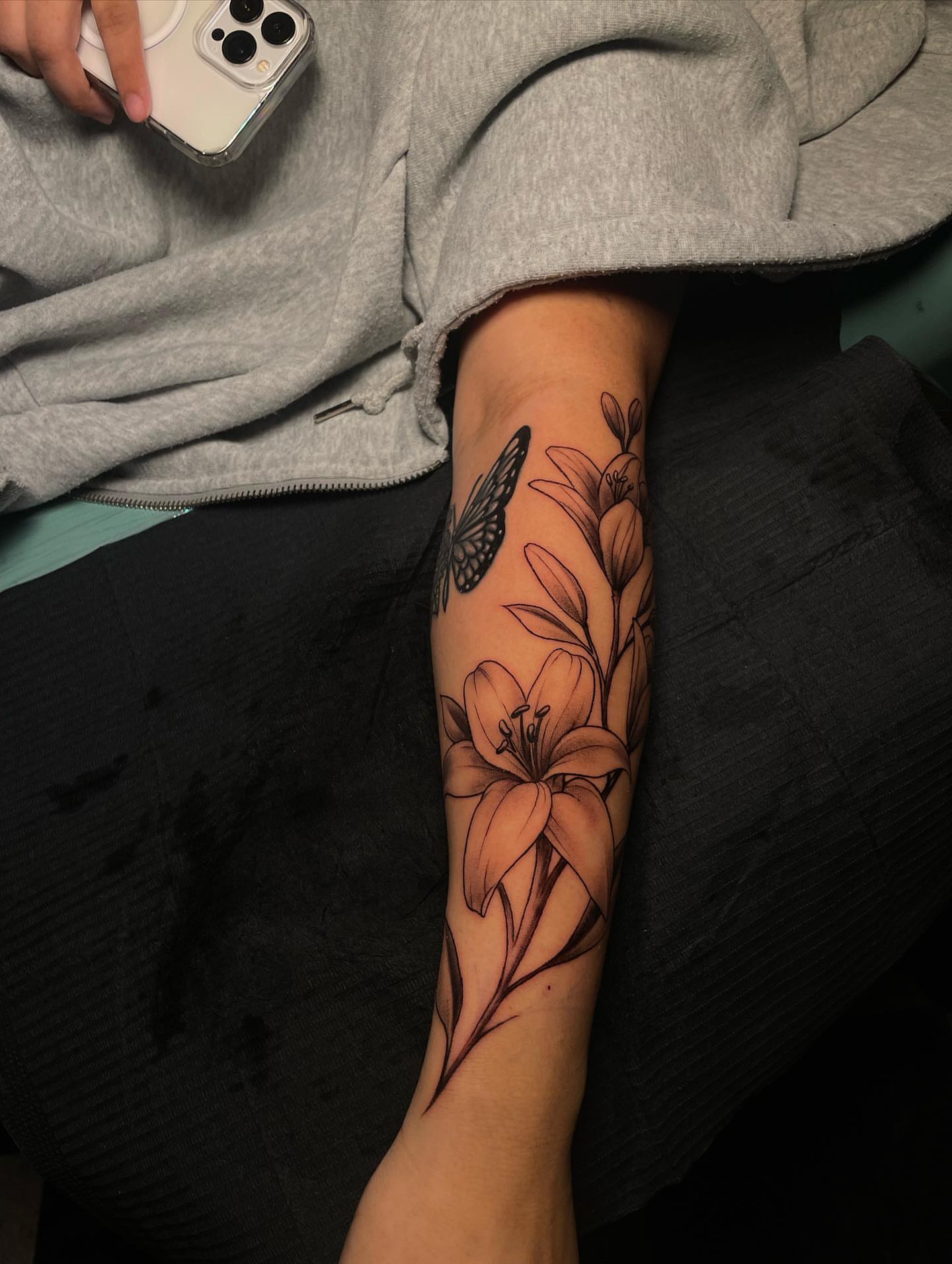 Lily and butterfly realism tattoo on the forearm by Nikko