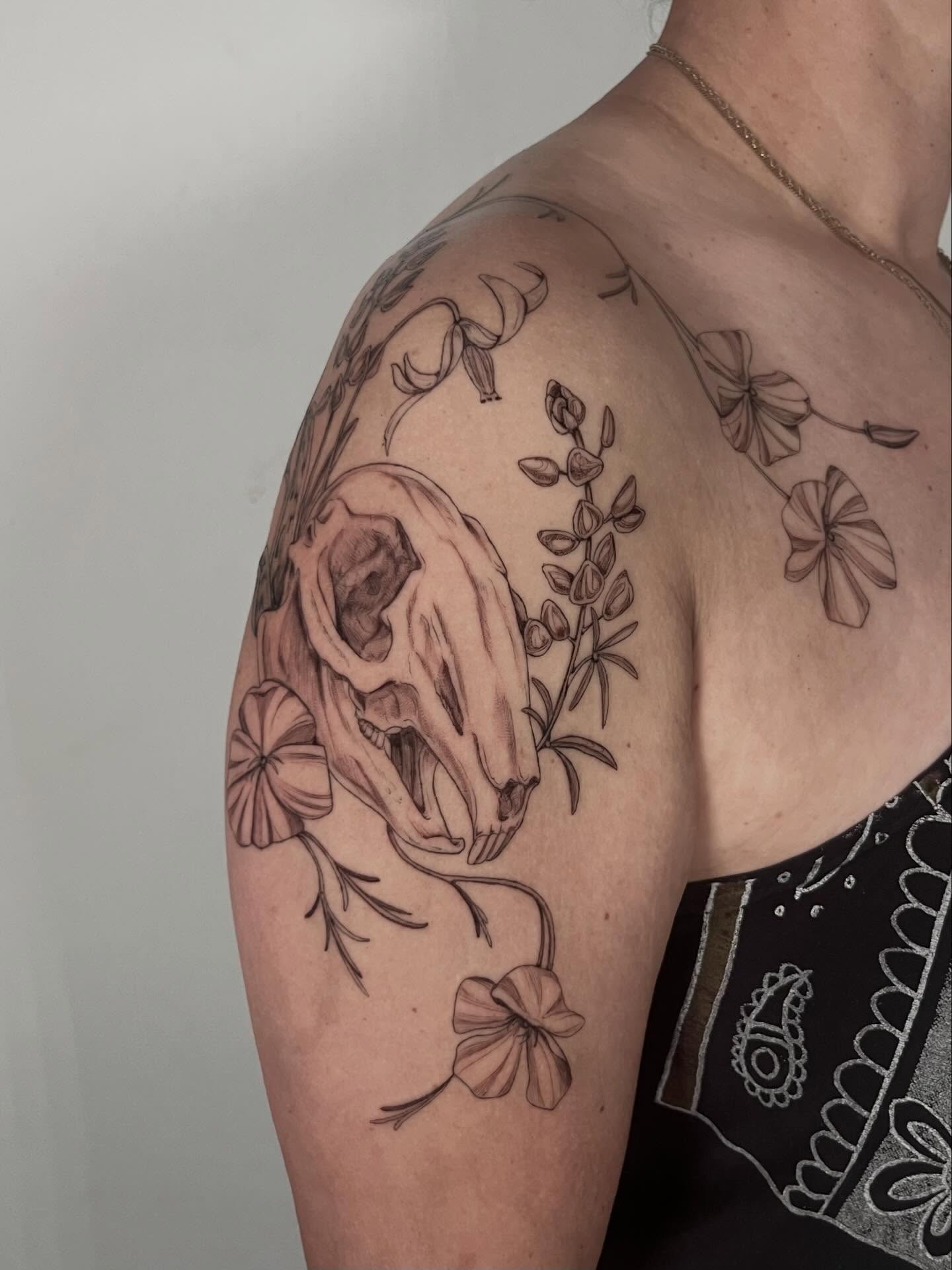 Skull and flowers realism tattoo on the shoulder by Sierra Skye